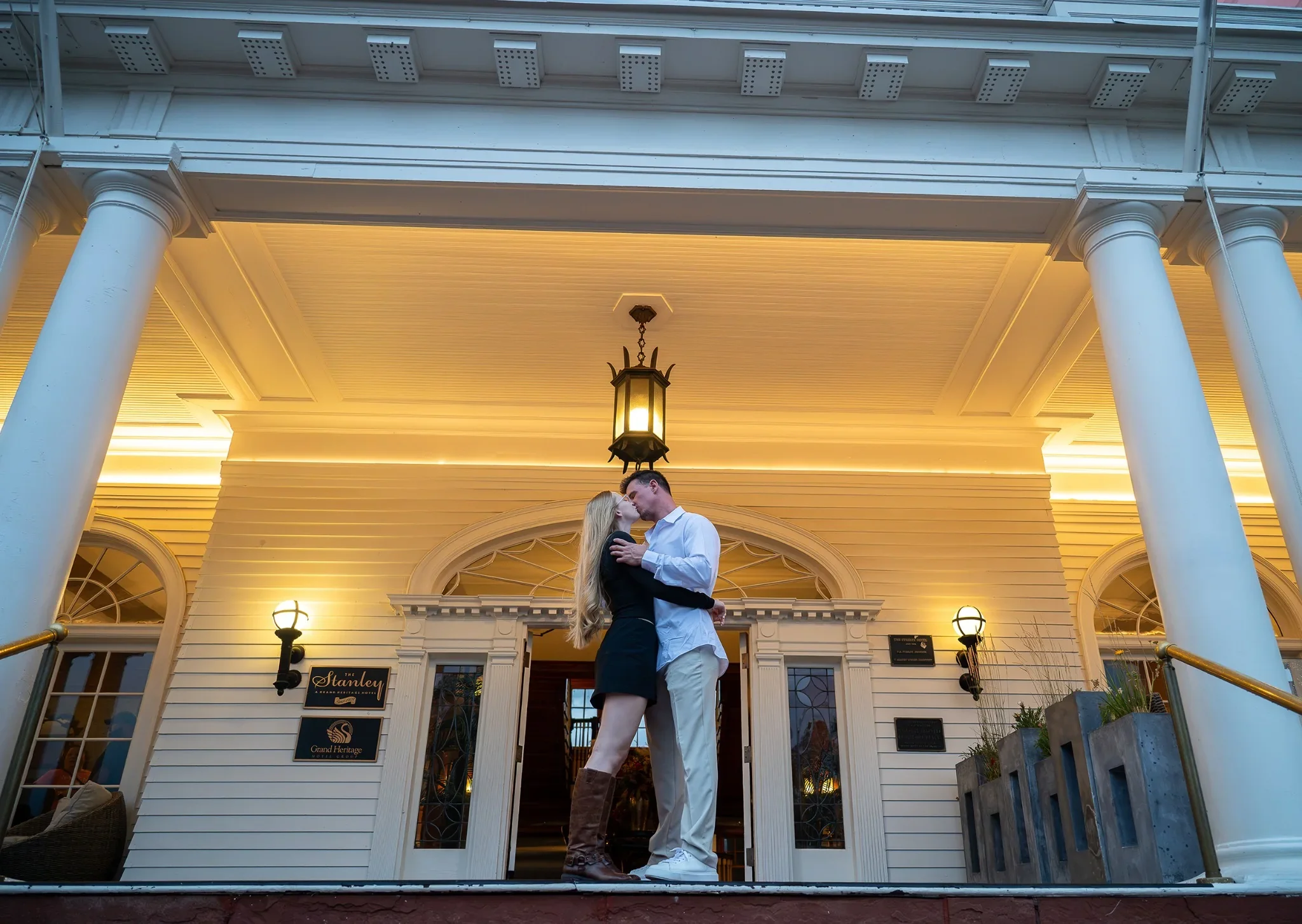 Couple passionately kissing in front of main entrance of Stanley Hotel in Estes Park. 