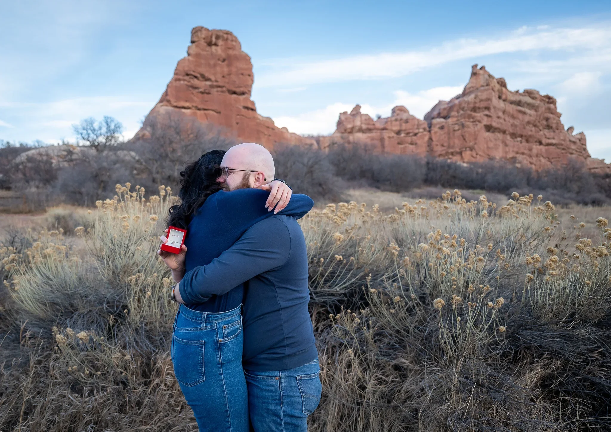 A couple lovingly embraces moments after getting engaged at South Valley Park in Littleton, Colorado captured by Ryan Kost. 