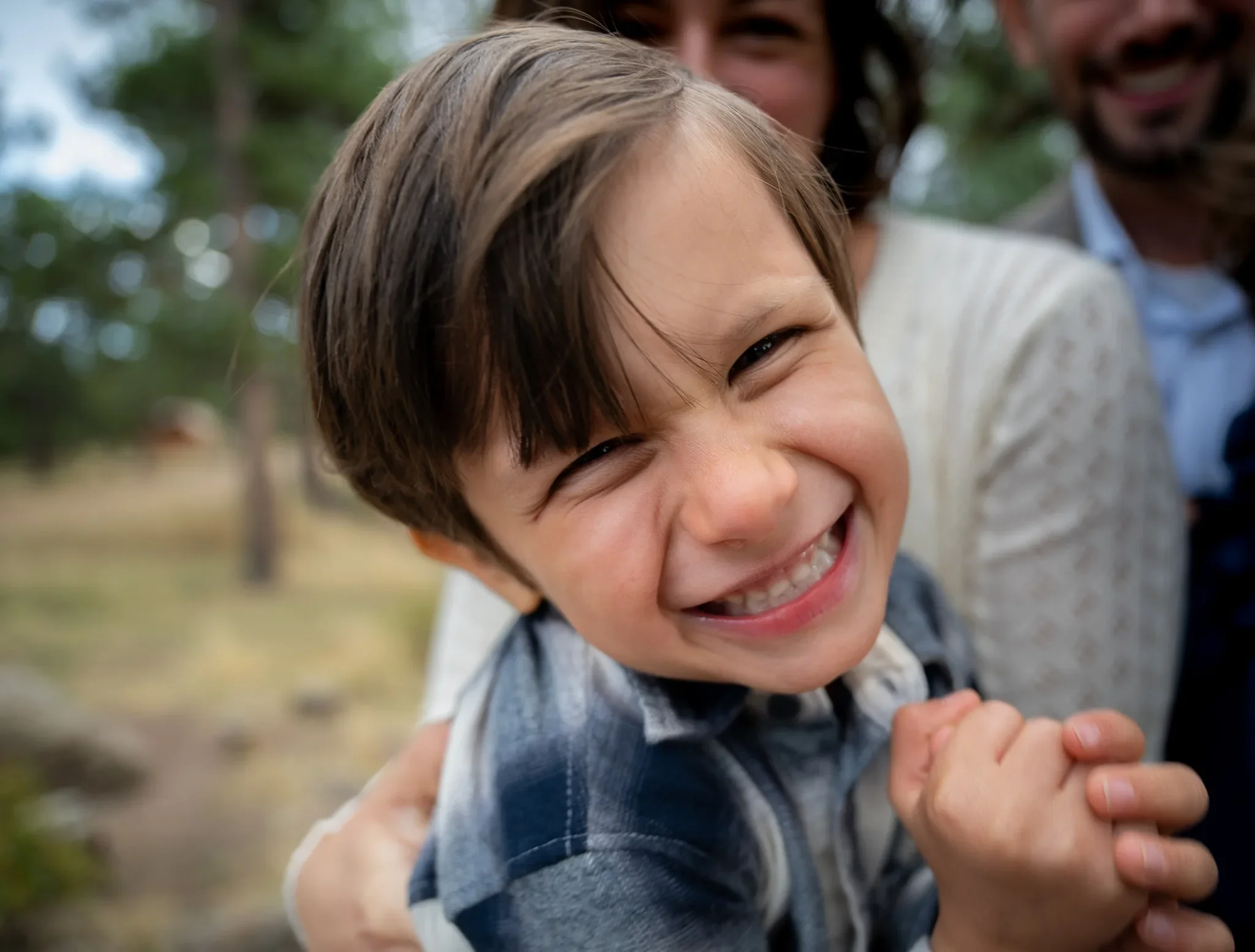 Close up of young boy grinning ear to ear with his natural smile.  Mount Falcon West Trailhead joyful family photography captured by Ryan Kost