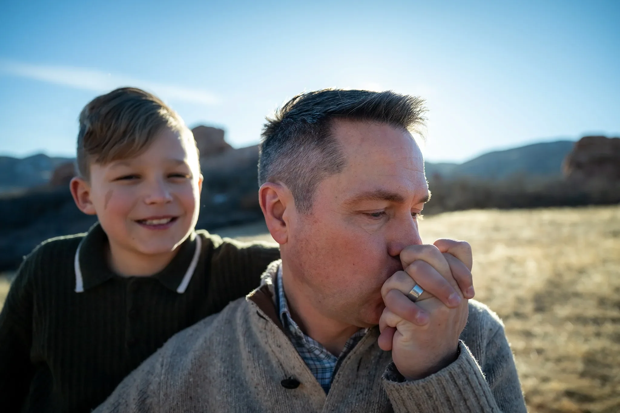 Dad kissing son's hand during an outdoor family photography session at South Valley Park Littleton Colorado.