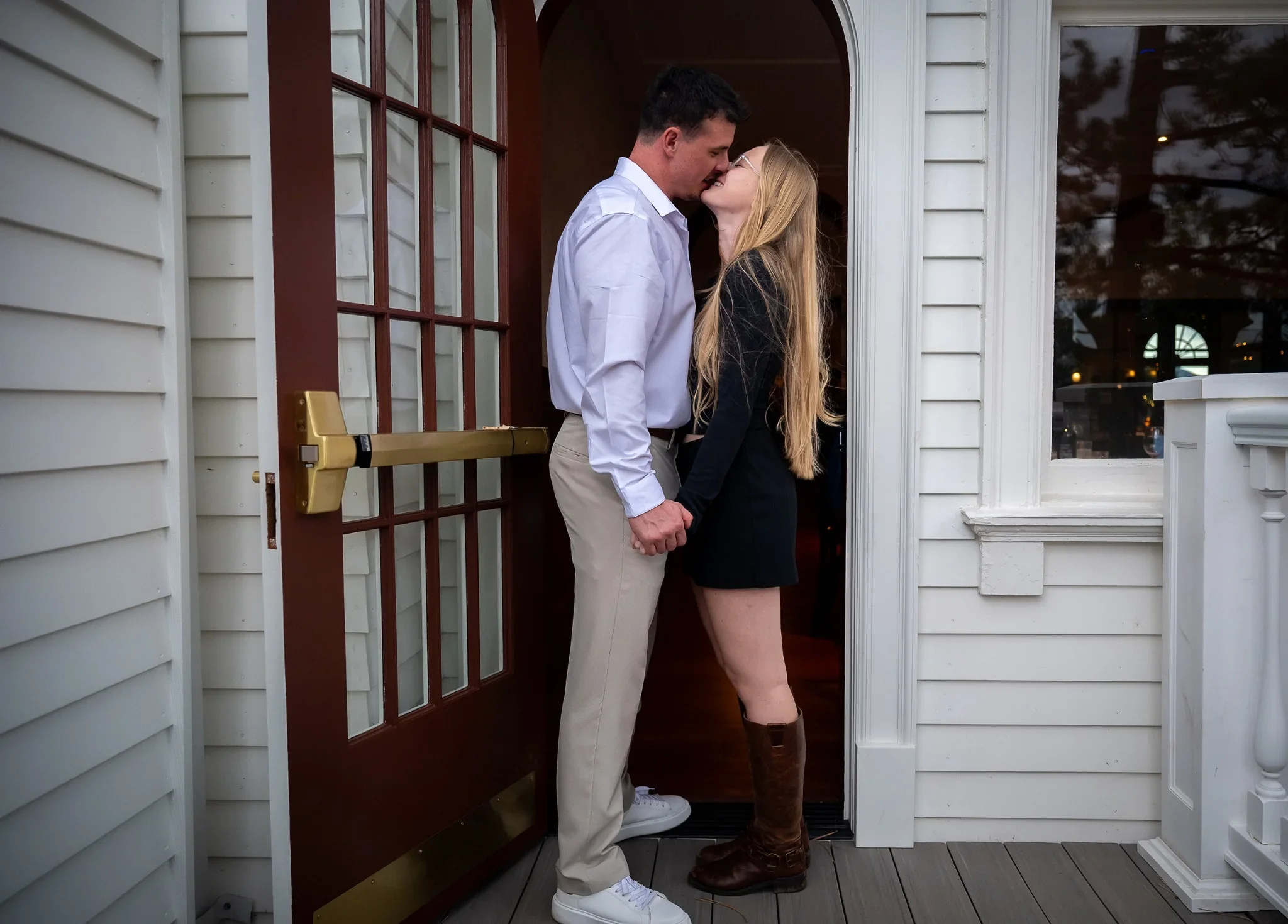 Couple kissing in doorway at Stanley Hotel in Estes Park during an en engagement session captured by Ryan Kost.