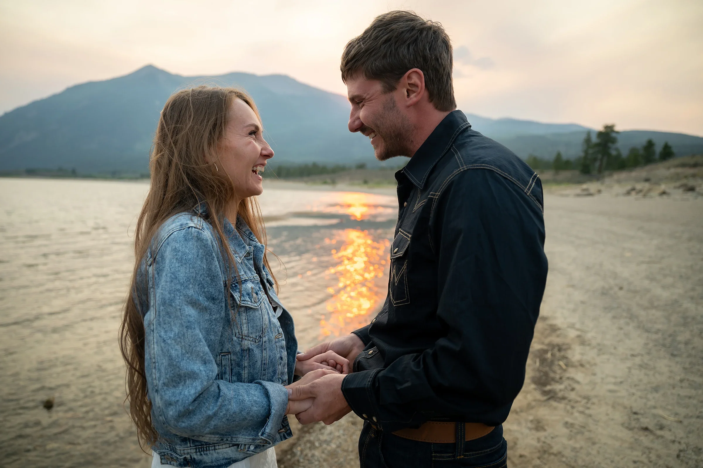 Newlywed couple holding hands and laughing at sunset during their Twin Lakes, Colorado elopement.