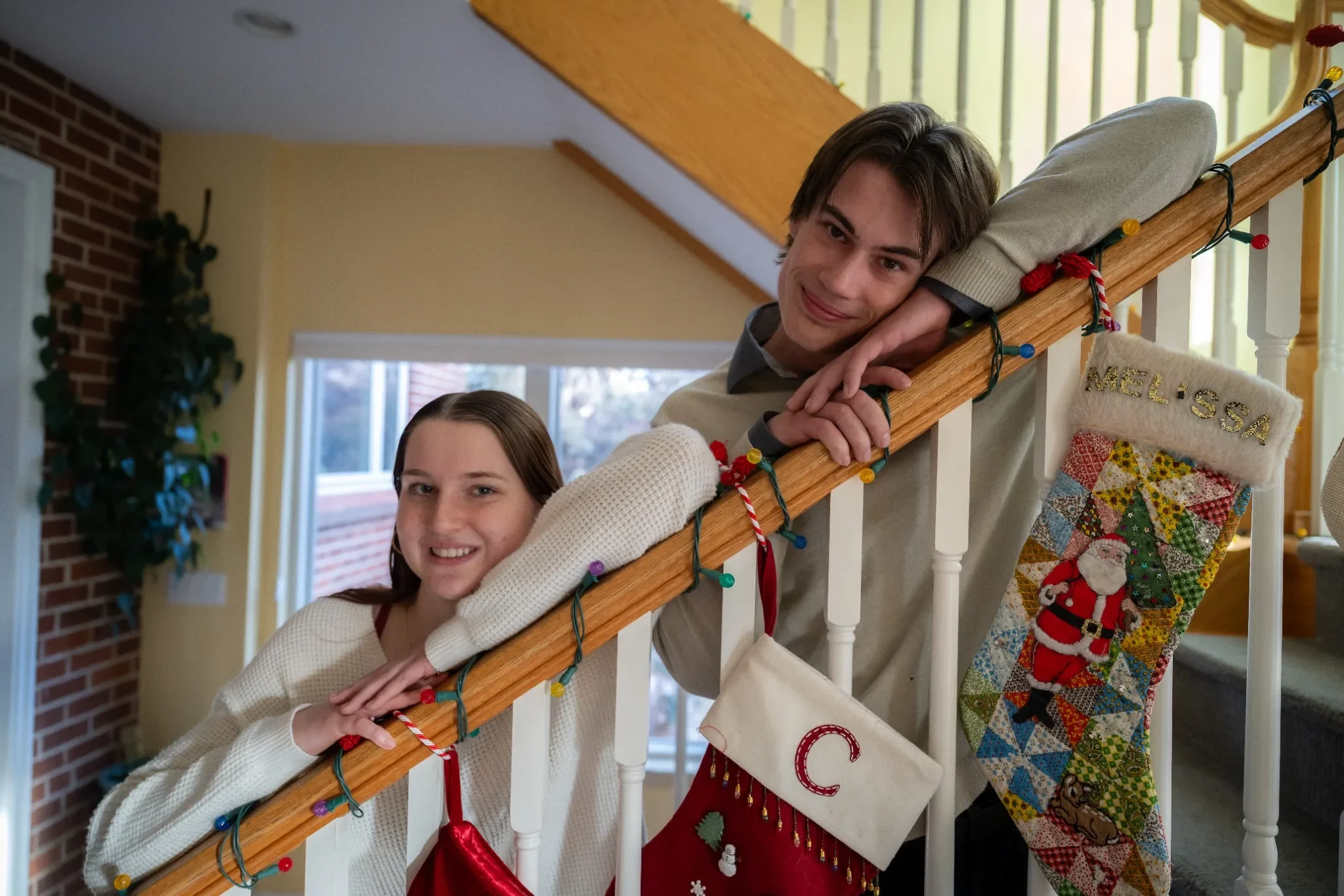 Siblings portrait on banister during holidays at a home photo session in Denver, Colorado captured by Ryan Kost