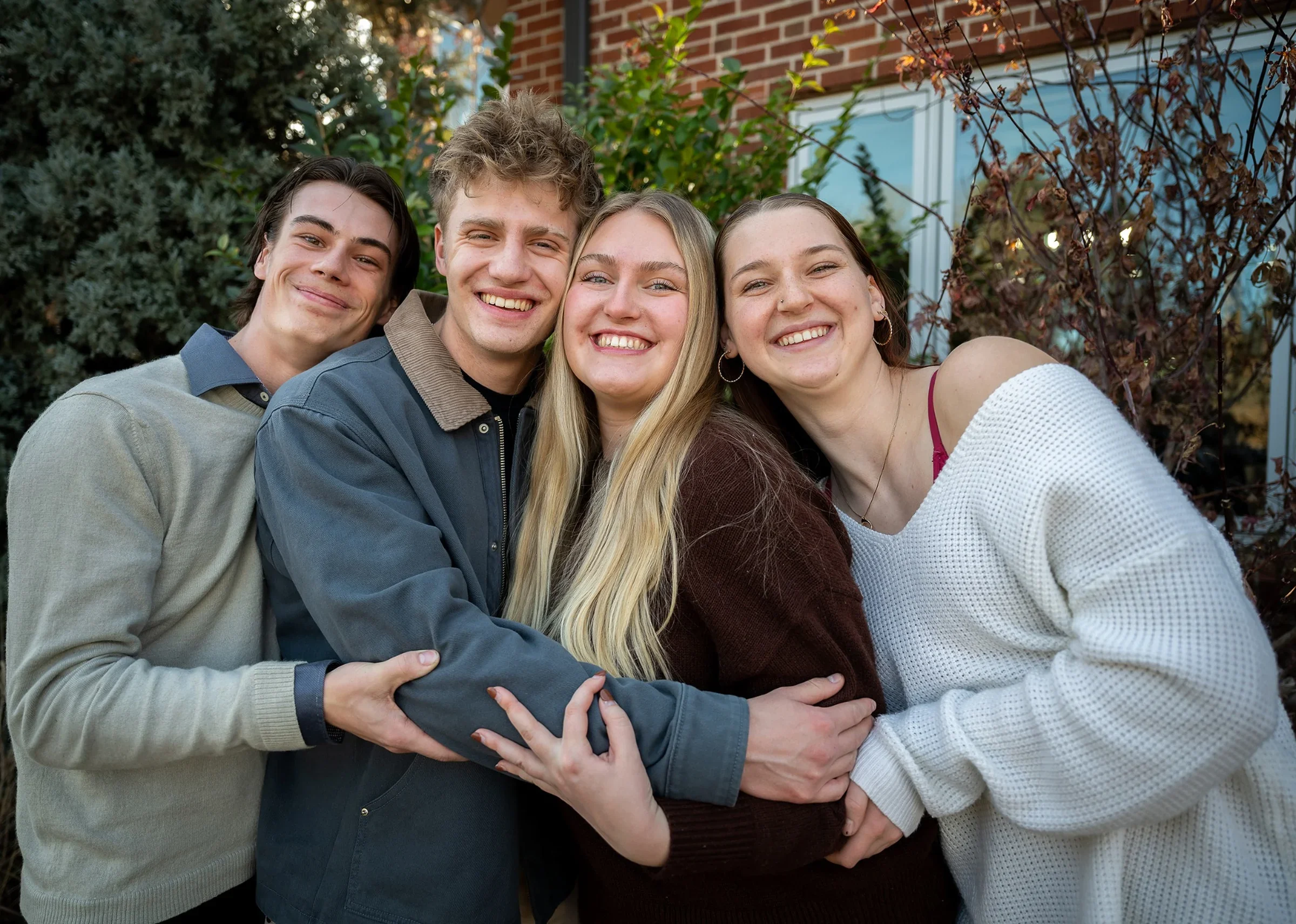 Relaxed at home family photo in Denver Colorado with siblings and cousins laughing, hugging, and enjoying a playful moment