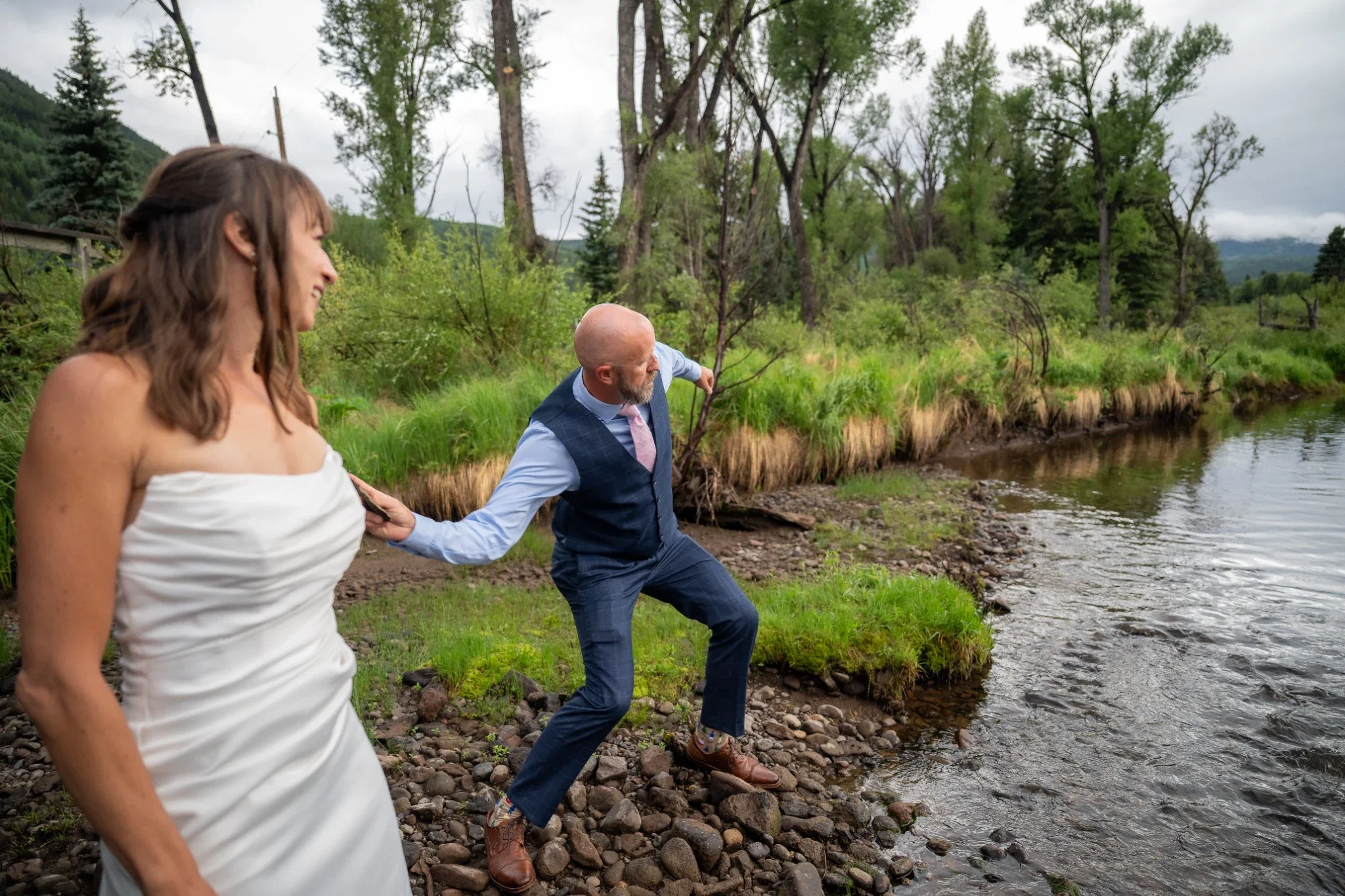 Bride and Groom having a rock skipping contest on the Conejos River in Horca, Colorado.