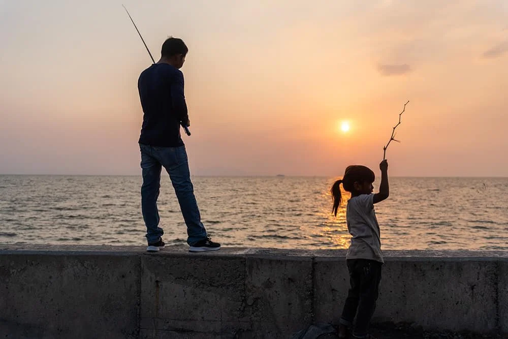 Daughter fishing with dad at sunset in Kep, Cambodia. Ryan Kost Photography