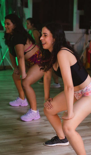 Women participating in a fitness class, wearing workout clothes, and performing a squat exercise.