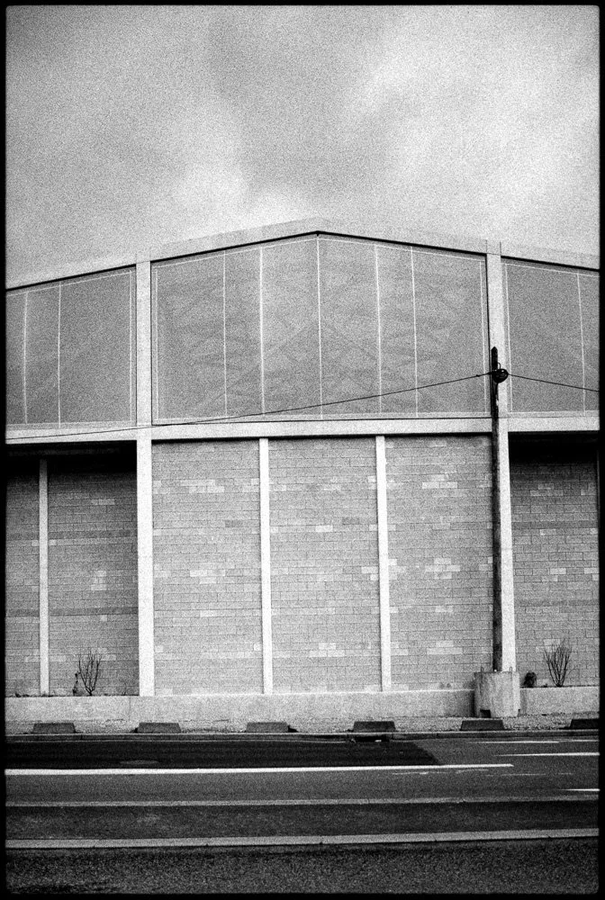 Une façade de bâtiment moderne avec des murs en briques et des fenêtres en verre, vue de face, sans personnes.