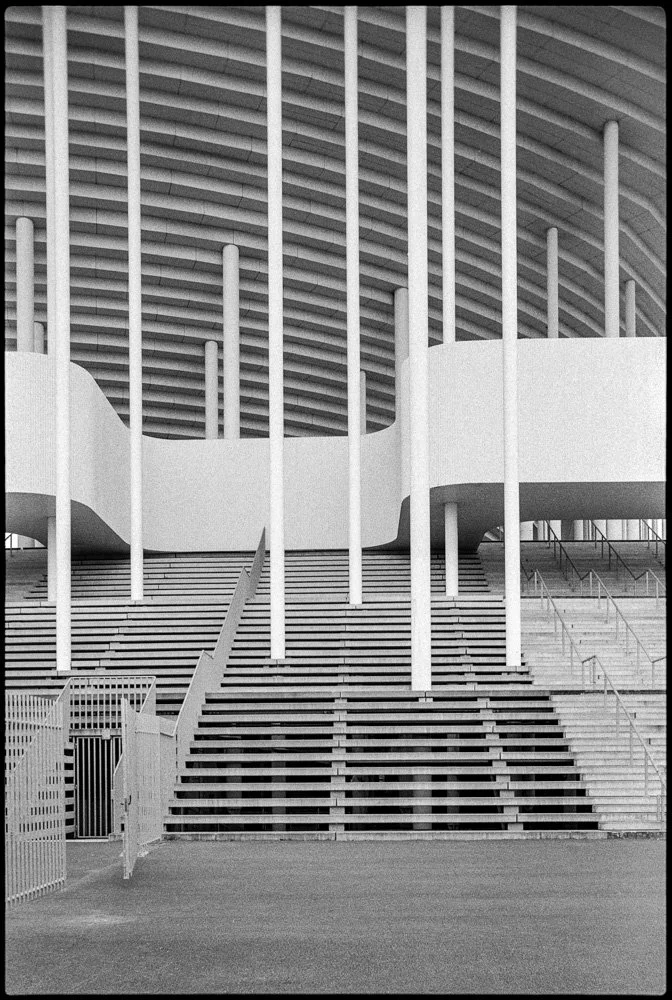 Structure moderne avec escaliers en bois, colonnes blanches et plafond arquée