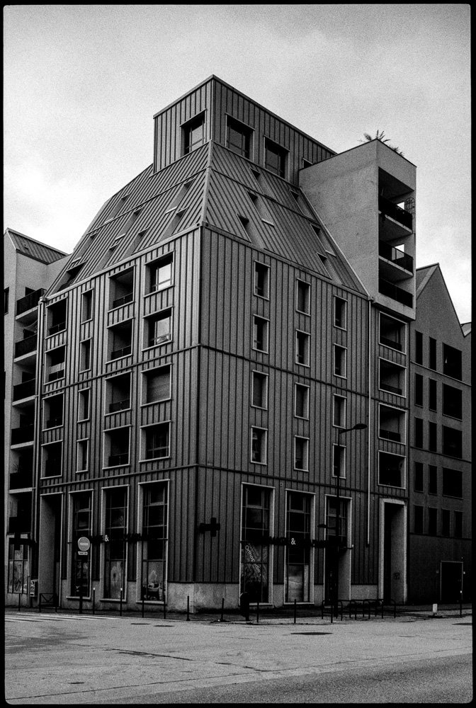 Bâtiment moderne avec façade en métal, plusieurs fenêtres et un design architectural unique.