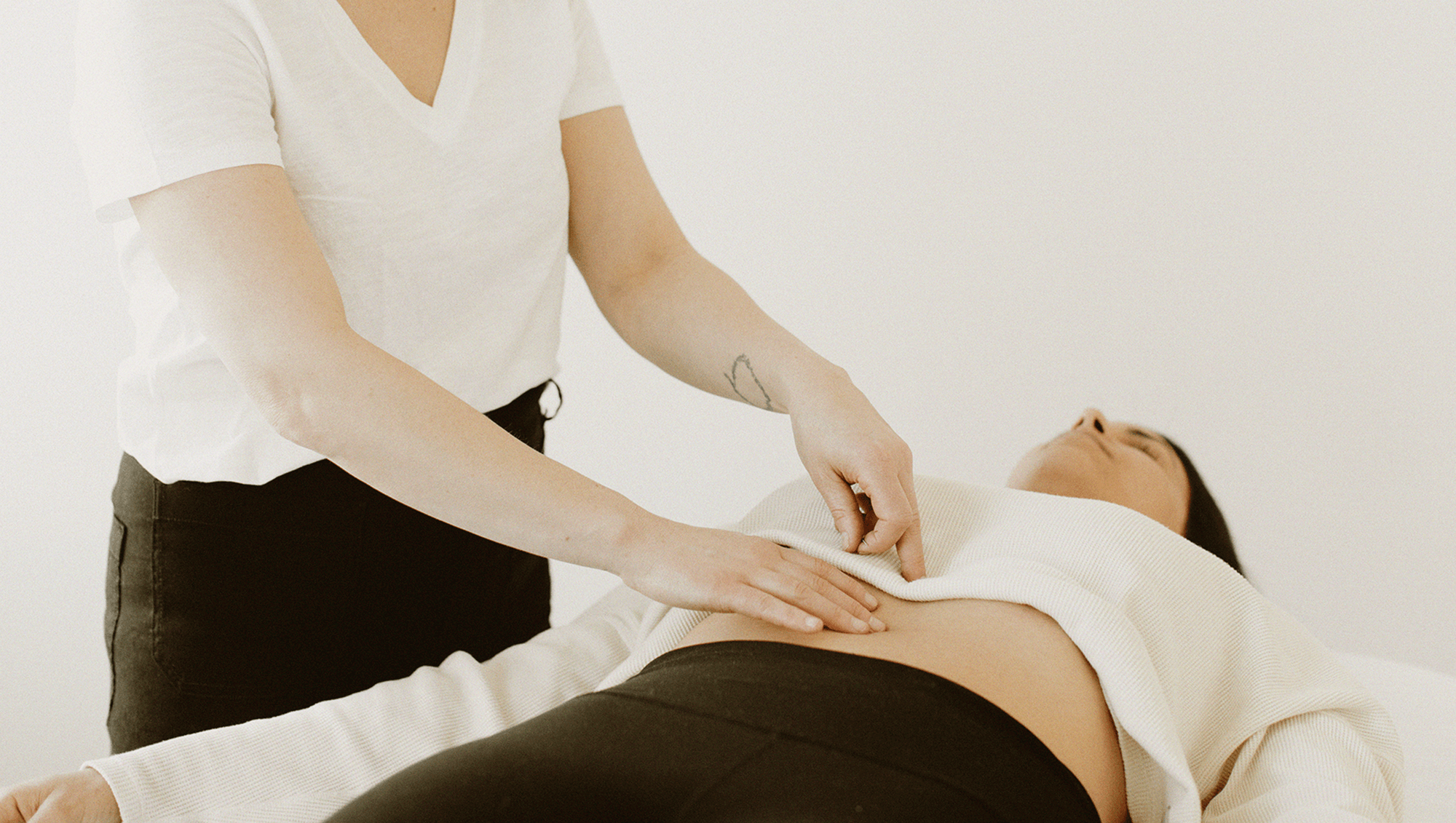 Person performing abdominal massage on a lying client in Denver