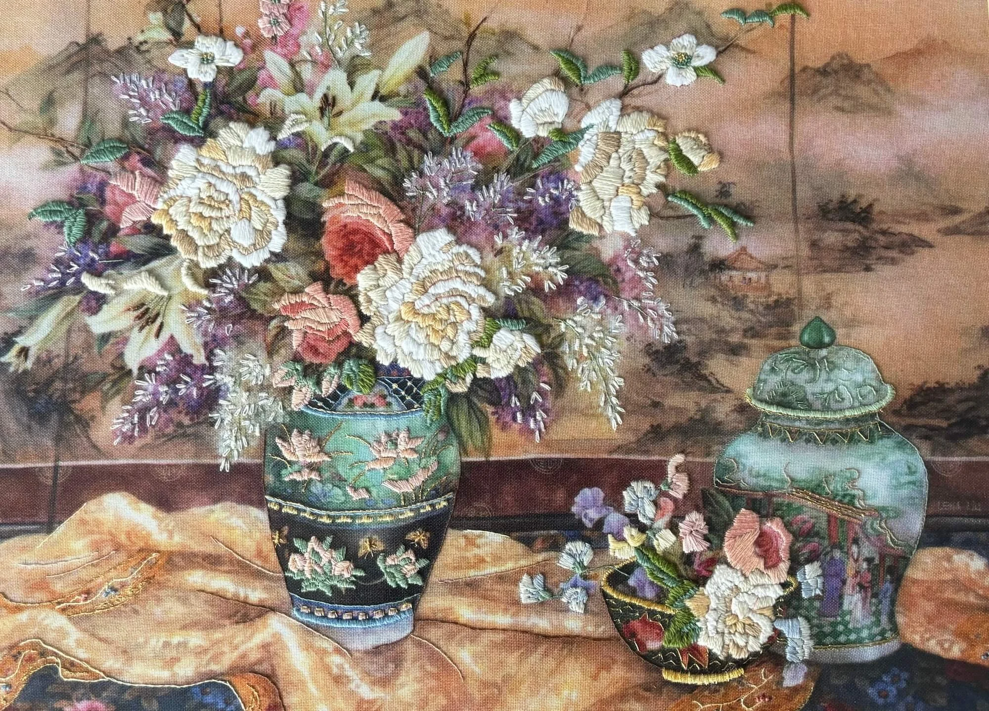 Bordado de dos floreros de cerámica azules con rosas de colores sobre una mesa