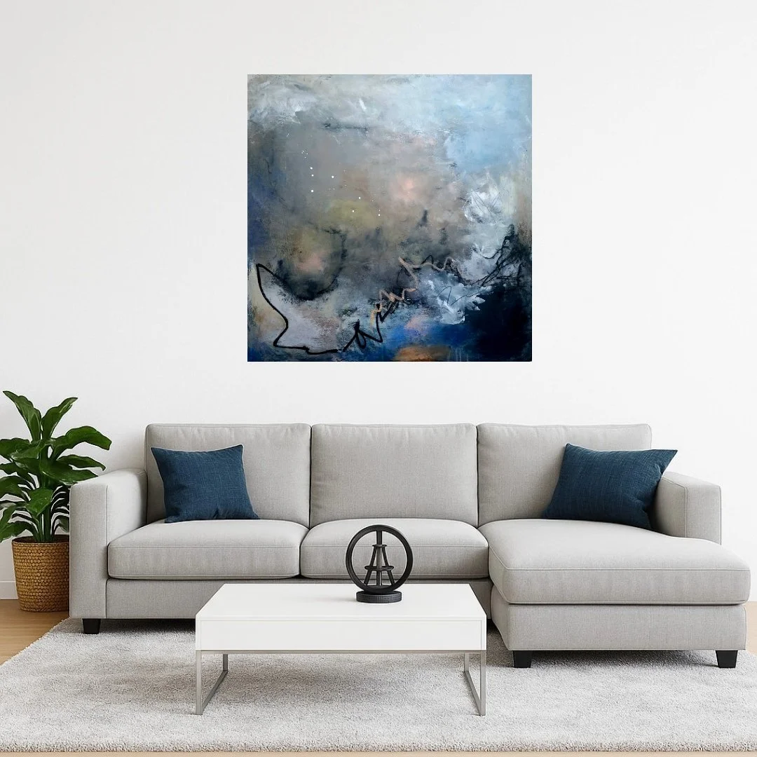 Living room with a light gray sofa, two dark blue pillows, a white coffee table with Eiffel Tower decor, green plant in a woven basket, and abstract art painting with blue and neutral tones on the wall.