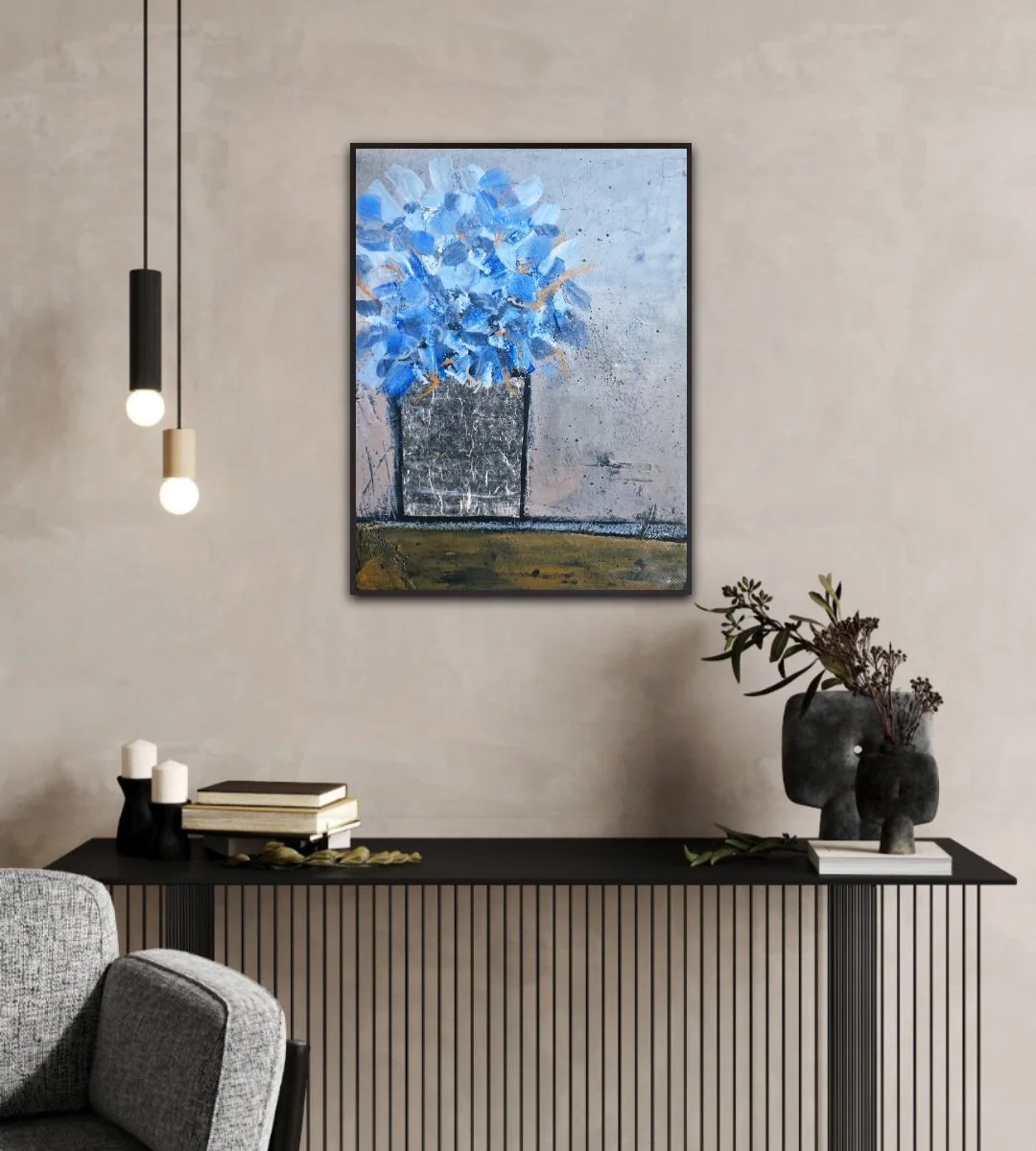 A modern interior with a beige wall, black sideboard, and wall art depicting abstract blue flowers in a black vase. Hanging from the ceiling are two pendant lights with black and white fixtures. On the sideboard are books, candles, and a vase with dried flowers.
