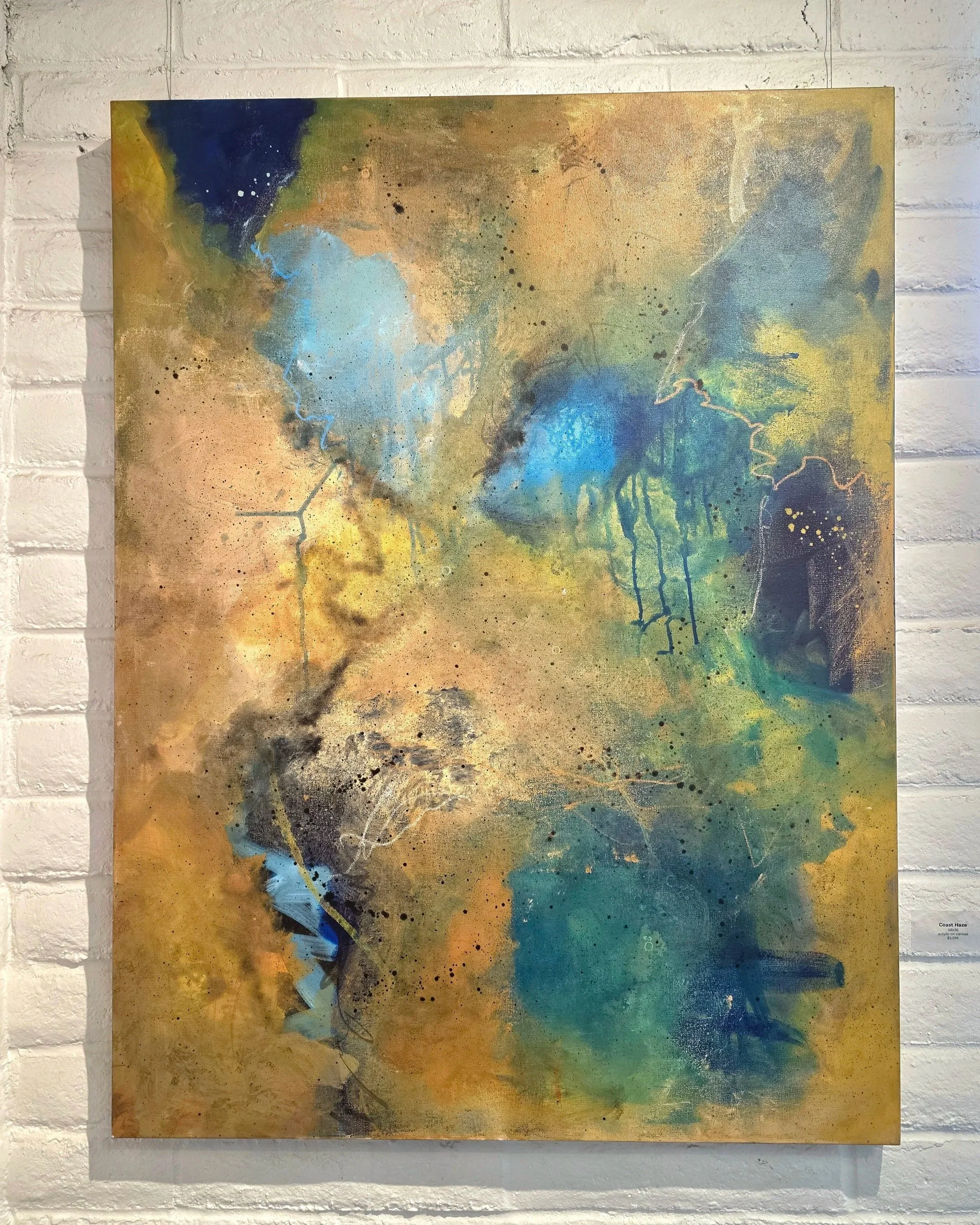 An abstract painting featuring splatters and streaks of blue, green, yellow, black, and brown on a textured canvas, mounted on a white brick wall.