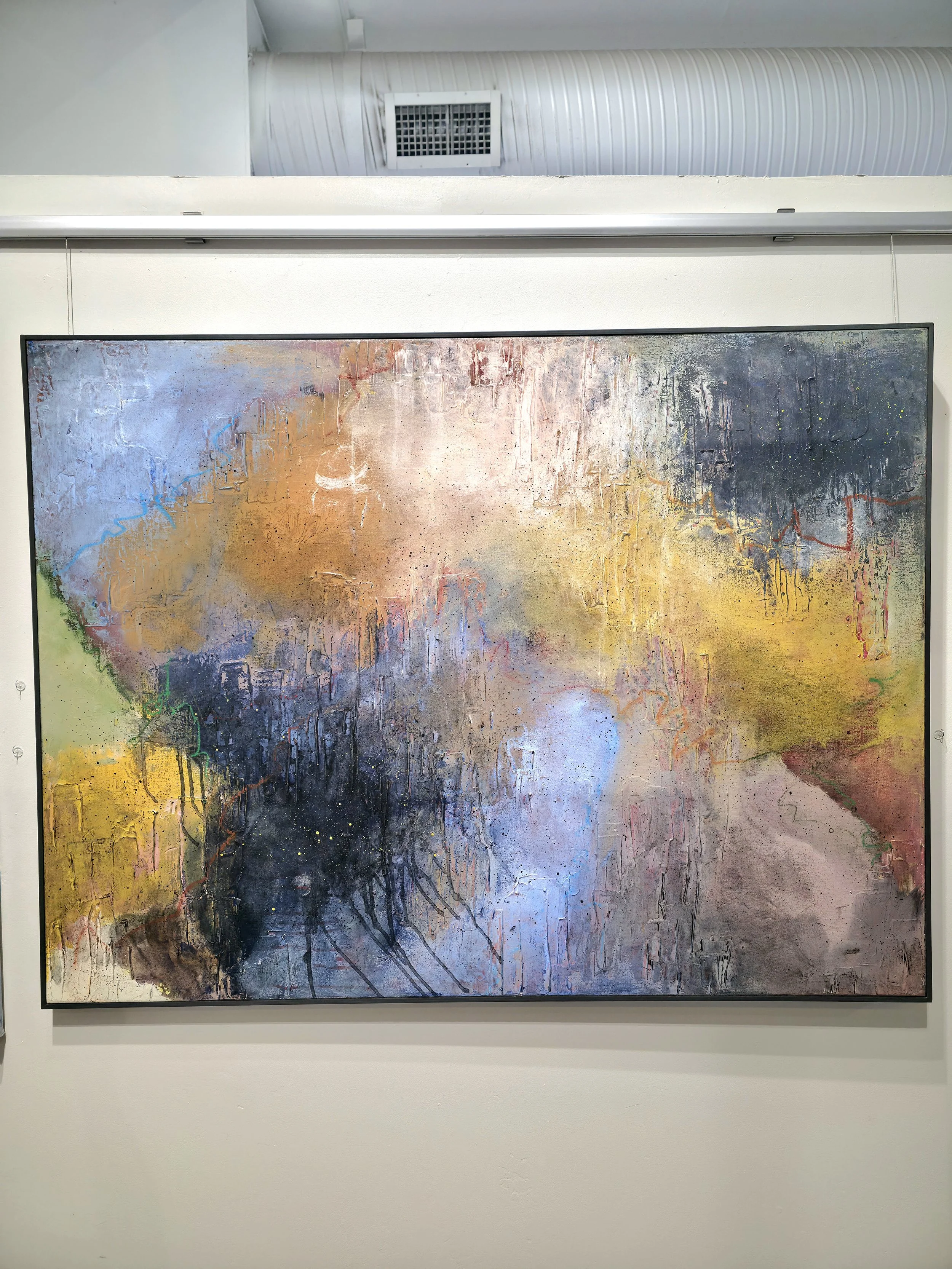 An abstract painting with a mix of colors including blue, purple, yellow, orange, black, and hints of green, with textured, layered brushstrokes and crackling details, framed and mounted on a white wall.