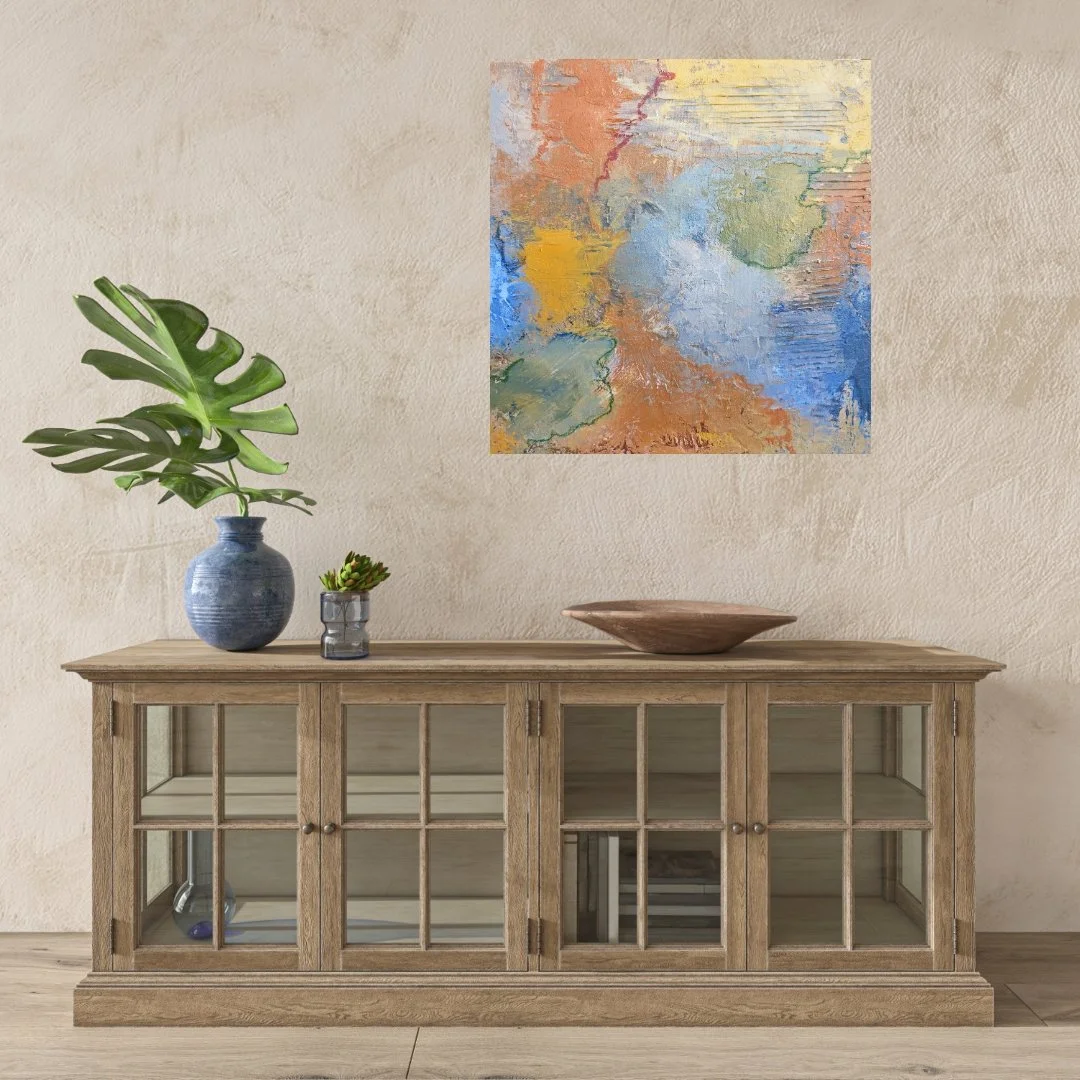A wooden sideboard with glass-paneled doors, topped with a large blue vase containing a monstera plant, a small glass jar with a succulent, and a wooden bowl. There is a colorful abstract painting on the wall above.