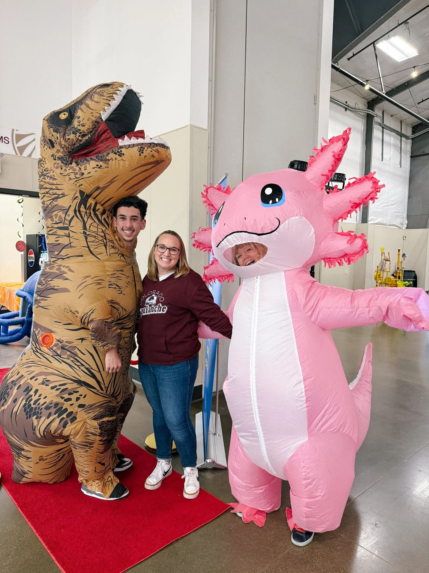 Our team dressed in sill blow-up costumes, a t-rex and axolotl at an event