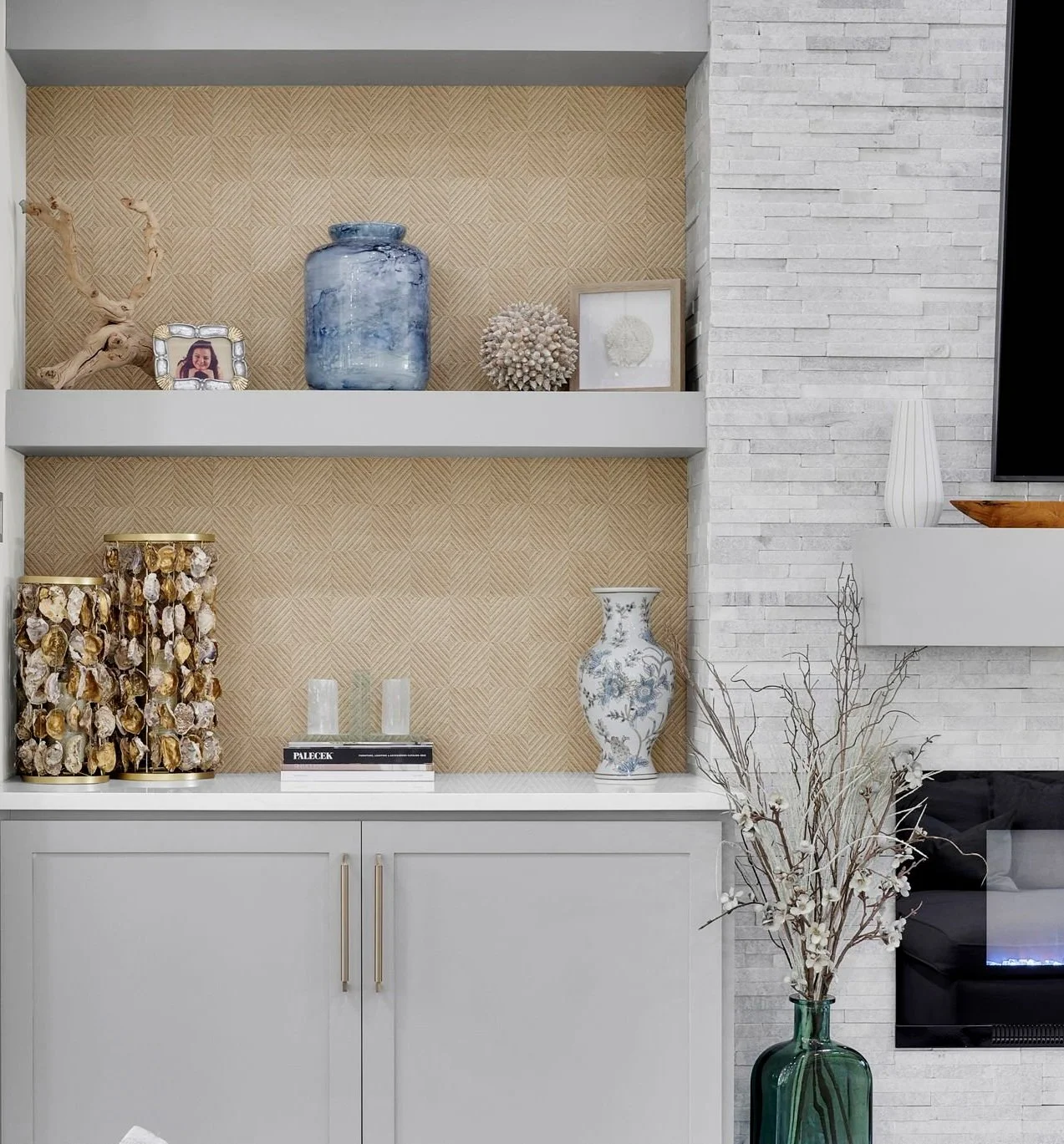 Decorative display with porcelain vase, framed picture, and decorative objects on shelves in a modern living room.