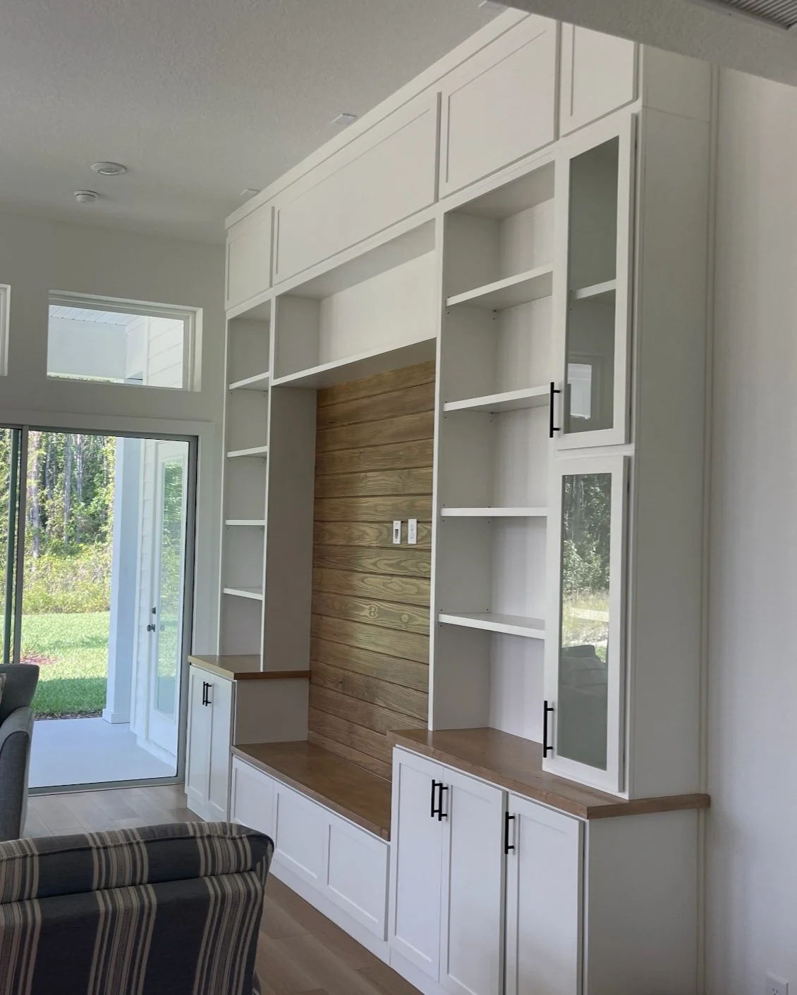 Built-in white and wood entertainment center with open shelves and cabinets in a modern living room.