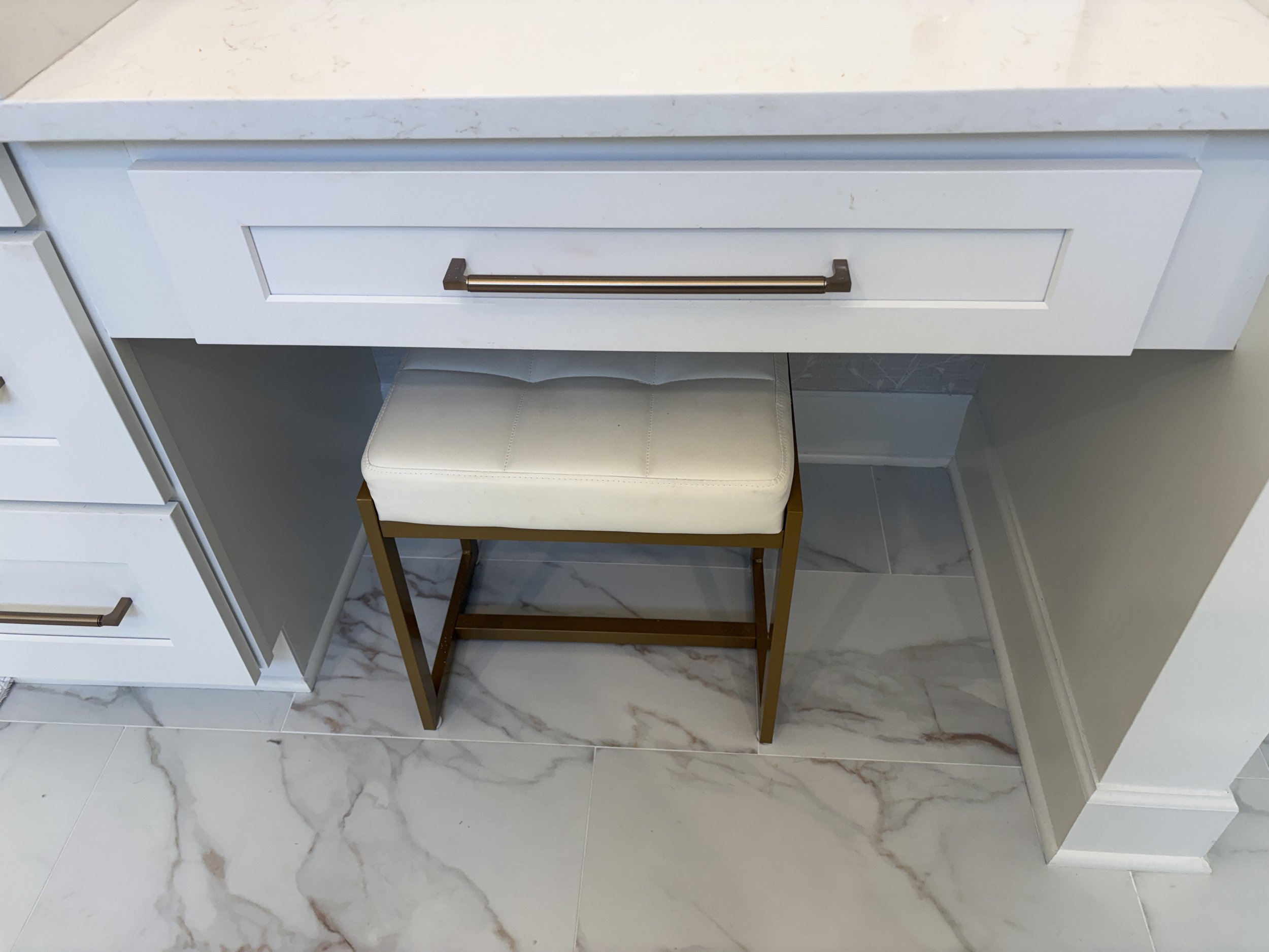 Finished primary bathroom featuring a custom built-in makeup vanity with quartz countertops, white shaker cabinetry, and a dedicated seating area designed for comfort and convenience. The thoughtfully integrated vanity station provides functional sto