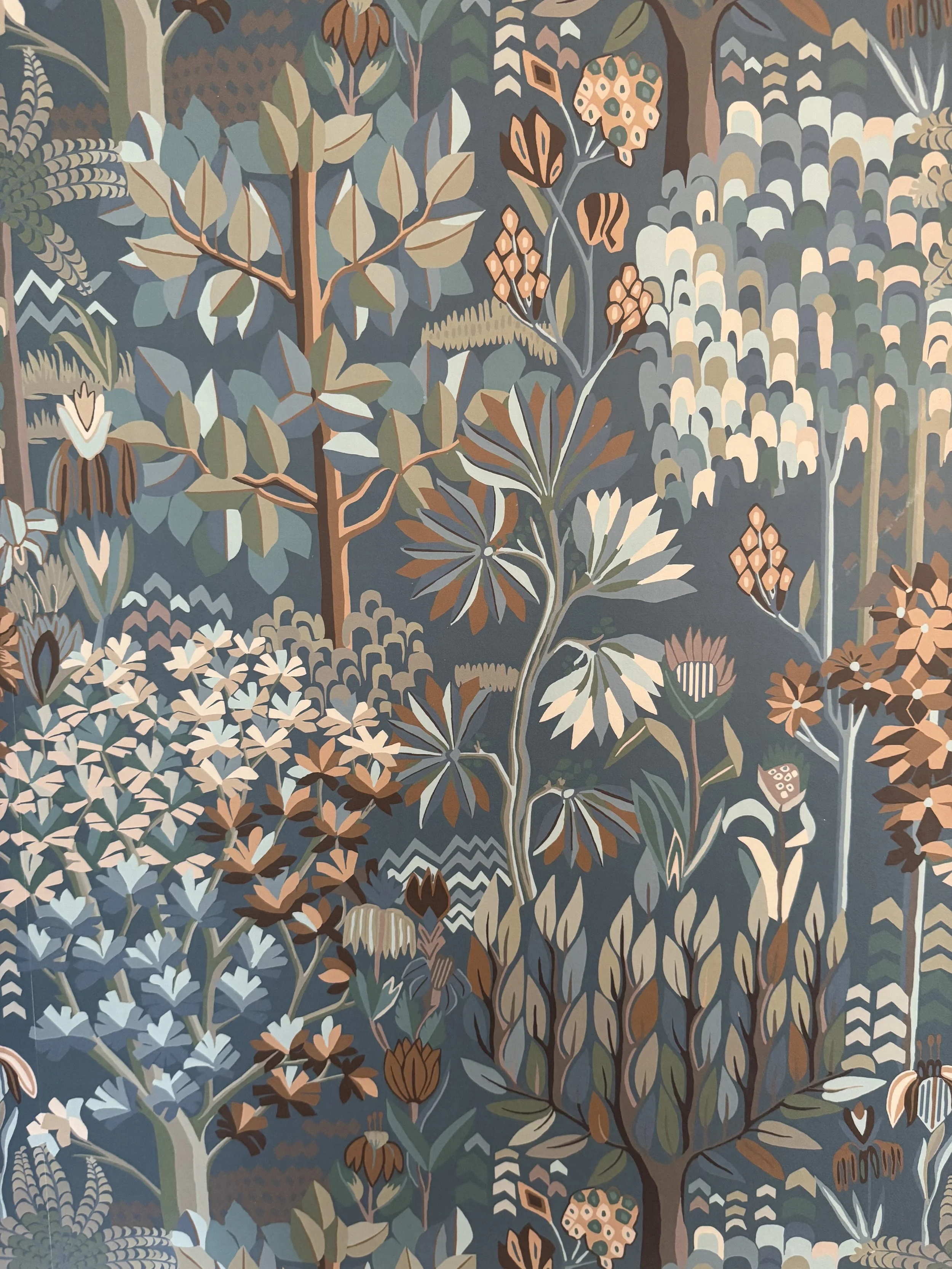 A detailed pattern of stylized trees, leaves, and flowers in earthy tones including muted greens, browns, creams, and oranges, creating a nature-inspired design.