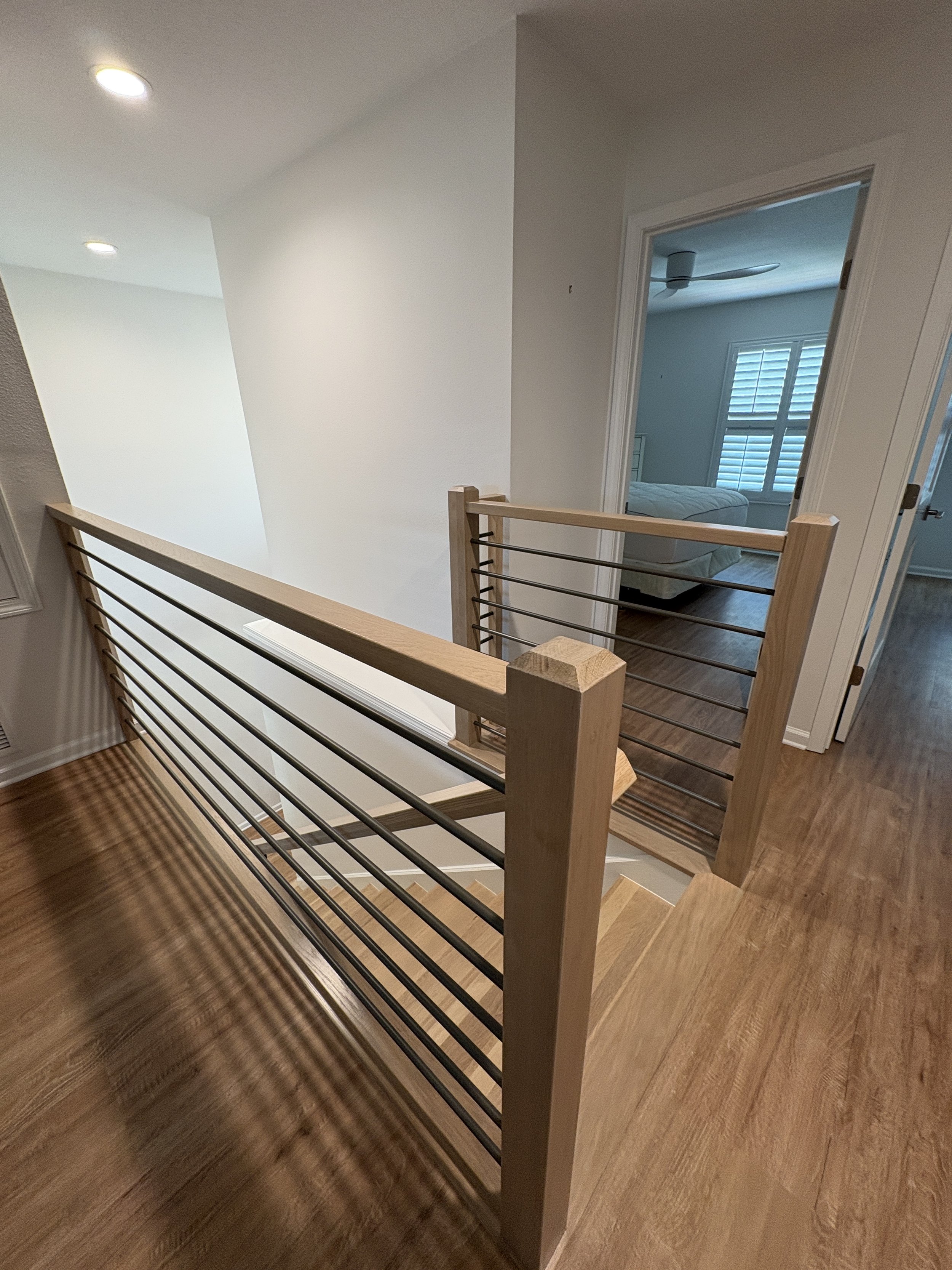 A modern horizontal metal balusters paired with natural wood handrails and stair treads gives this high-end Jacksonville condo remodel a clean, contemporary look. This custom staircase renovation was completed by Elite Construction of JAX.