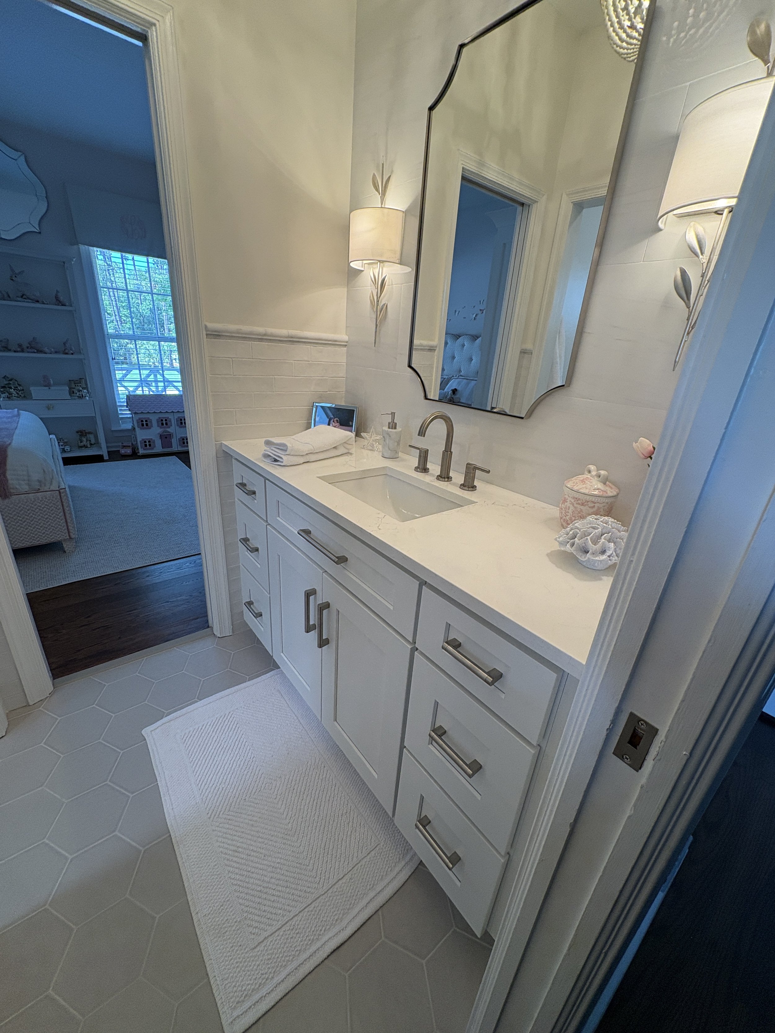Finished bathroom vanity featuring custom light-gray shaker cabinetry, quartz countertops, and an undermount sink accented by brushed nickel fixtures and elegant decorative hardware. The spacious vanity design provides ample storage and countertop sp