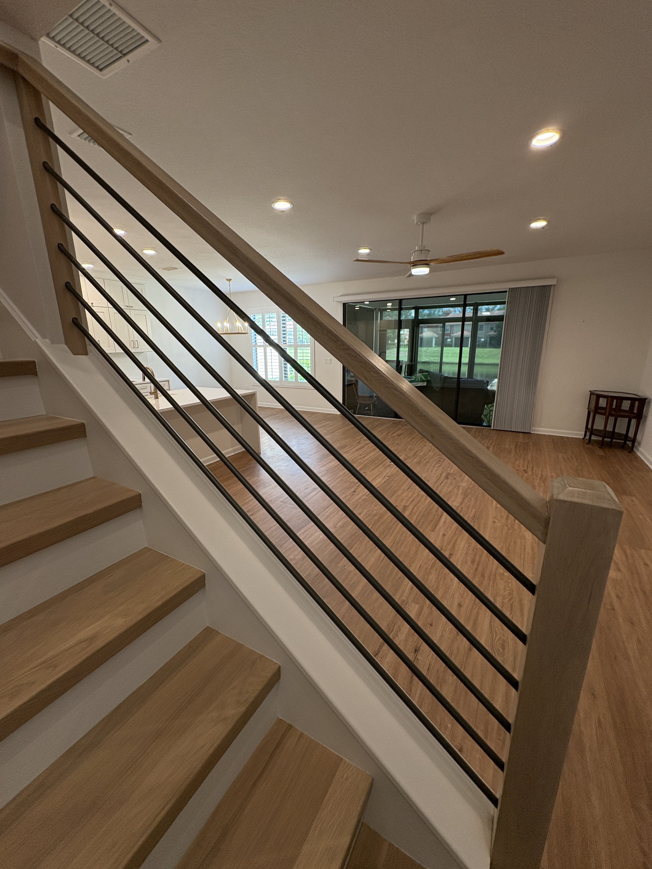 A modern horizontal metal balusters paired with natural wood handrails and stair treads gives this high-end Jacksonville condo remodel a clean, contemporary look. This custom staircase renovation was completed by Elite Construction of JAX.