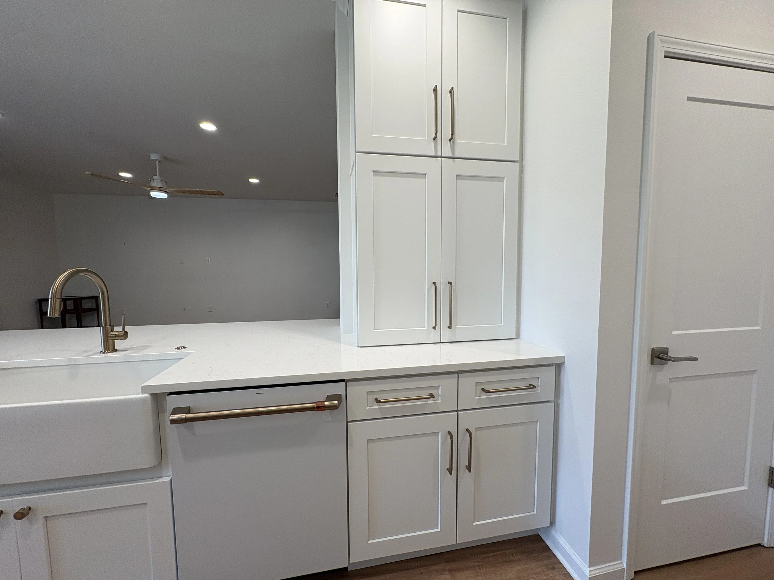 This high-end Jacksonville condo remodel features custom white cabinetry, an apron-front sink, sleek countertops, and brushed gold hardware for a bright, refined kitchen. Elite Construction of JAX provides luxury kitchen and full-condo renovations th