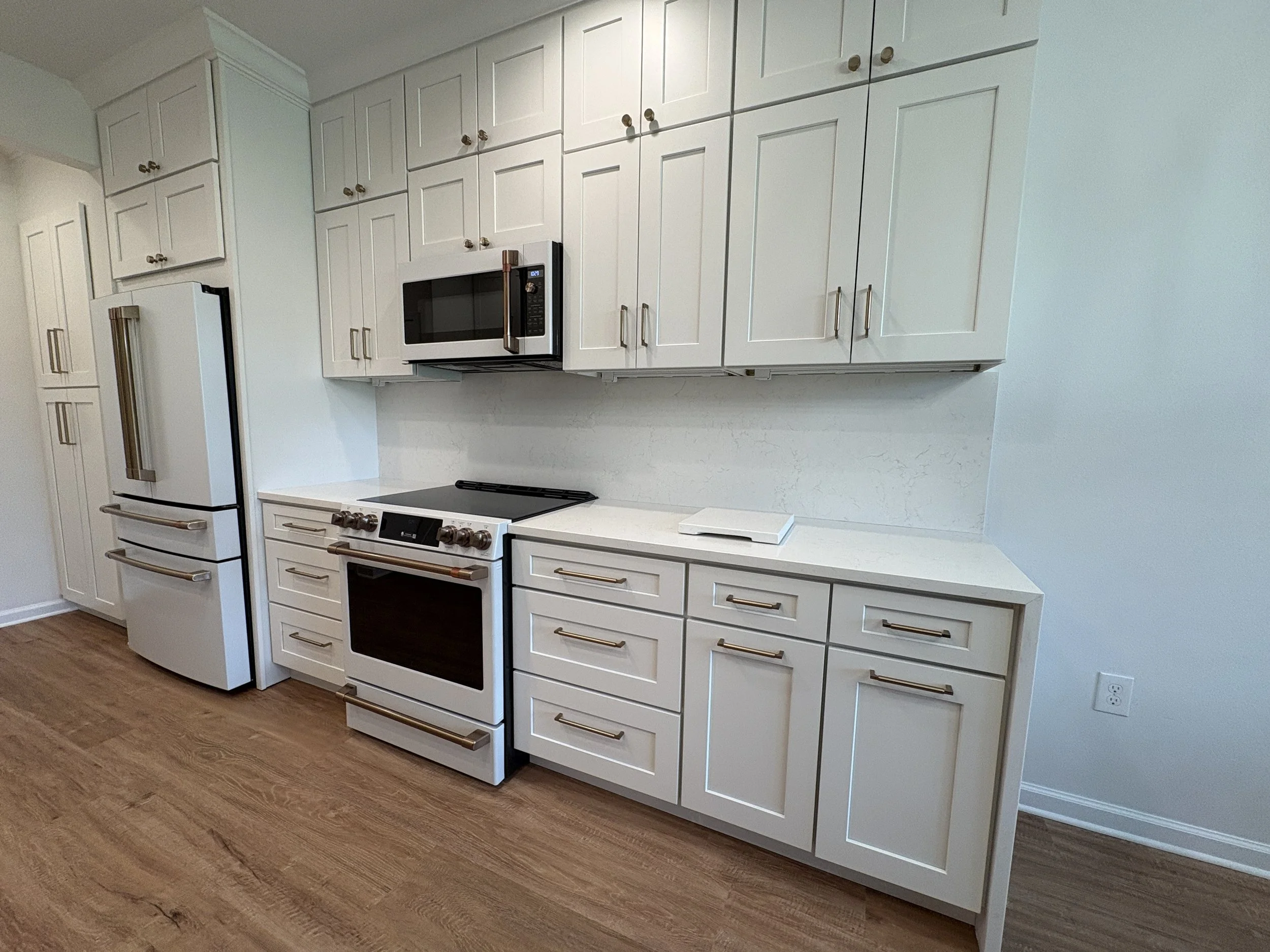 Floor-to-ceiling custom cabinetry, modern appliances, polished countertops, and warm wood-look flooring give this high-end Jacksonville condo kitchen a bright, sophisticated finish. Elite Construction of JAX specializes in luxury kitchen remodeling a