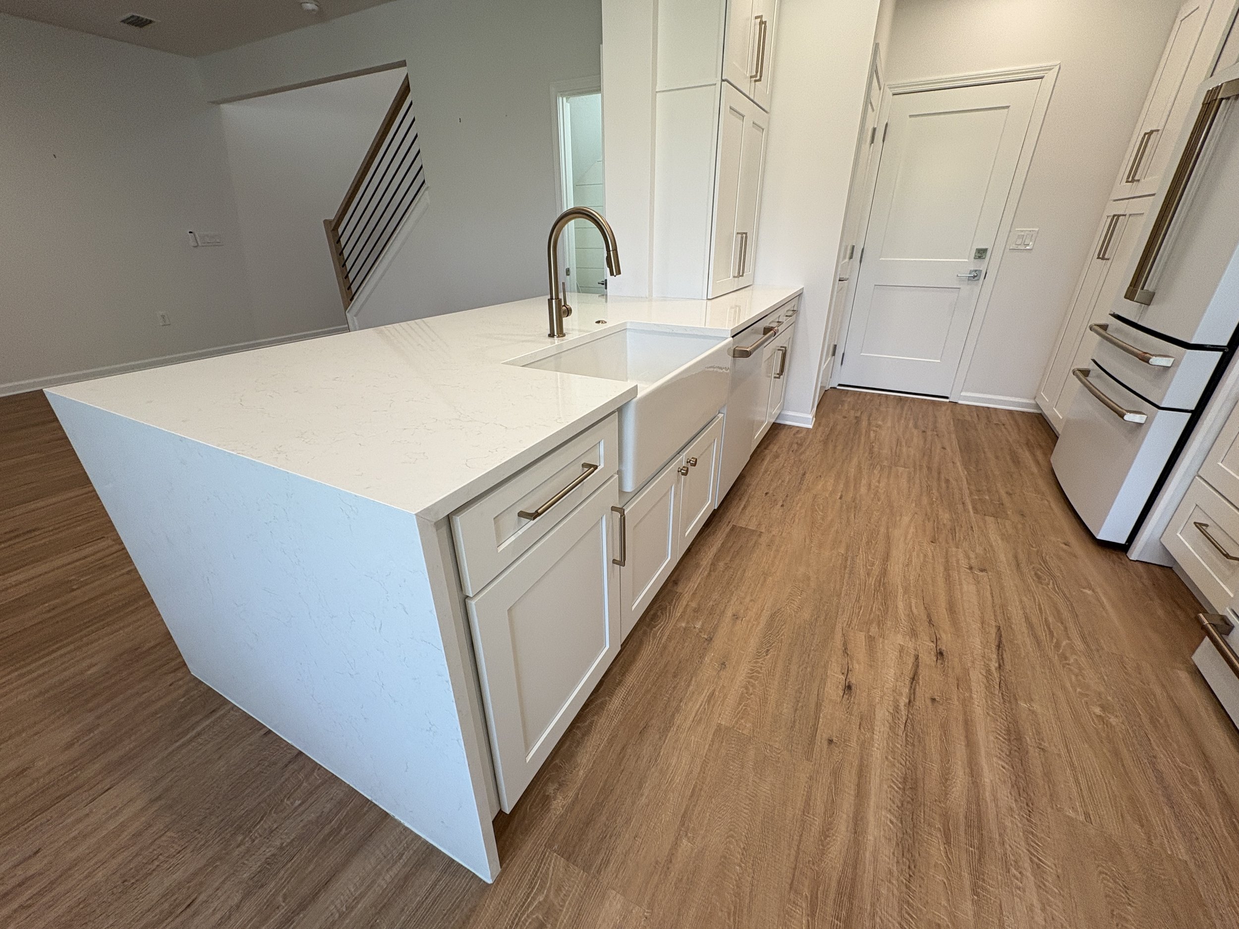 This high-end Jacksonville condo kitchen remodel features a spacious waterfall-edge island, custom white cabinetry, modern appliances, and warm wood-look flooring. Elite Construction of JAX creates polished, functional interiors throughout Jacksonvil