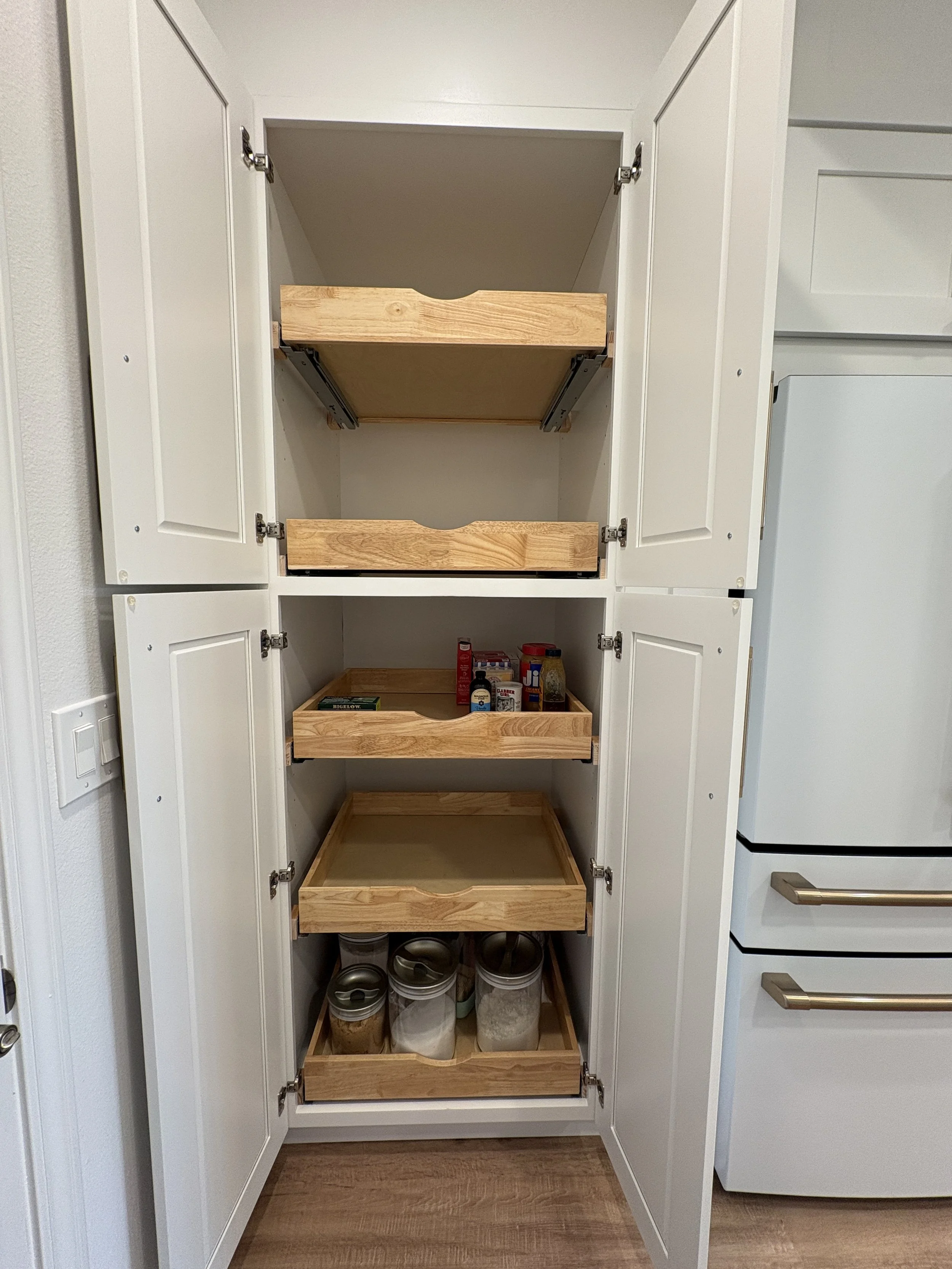 A custom pull-out pantry adds convenient, organized storage while maintaining the clean cabinetry design of this high-end Jacksonville condo kitchen remodel by Elite Construction of JAX.