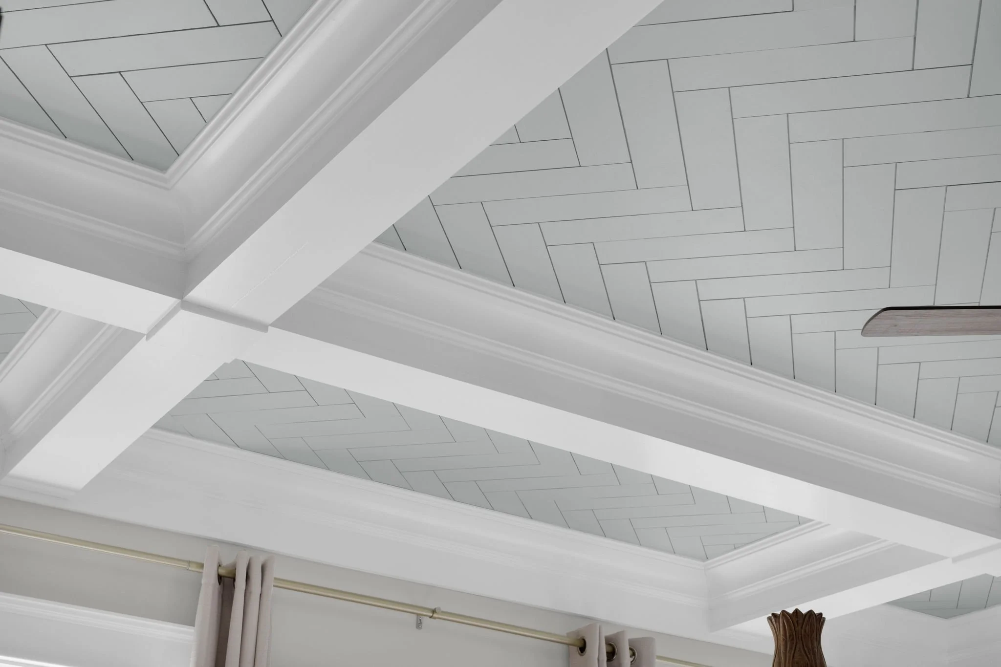 Ceiling with decorative crown molding and recessed lighting panels with geometric design.