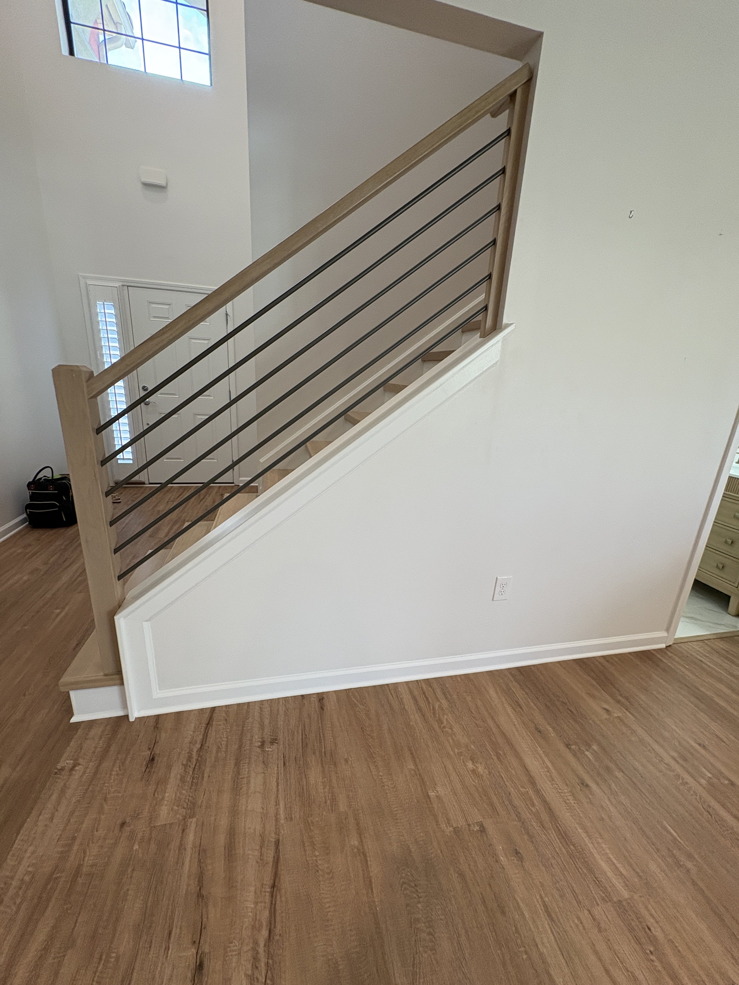 A modern horizontal metal balusters paired with natural wood handrails and stair treads gives this high-end Jacksonville condo remodel a clean, contemporary look. This custom staircase renovation was completed by Elite Construction of JAX.
