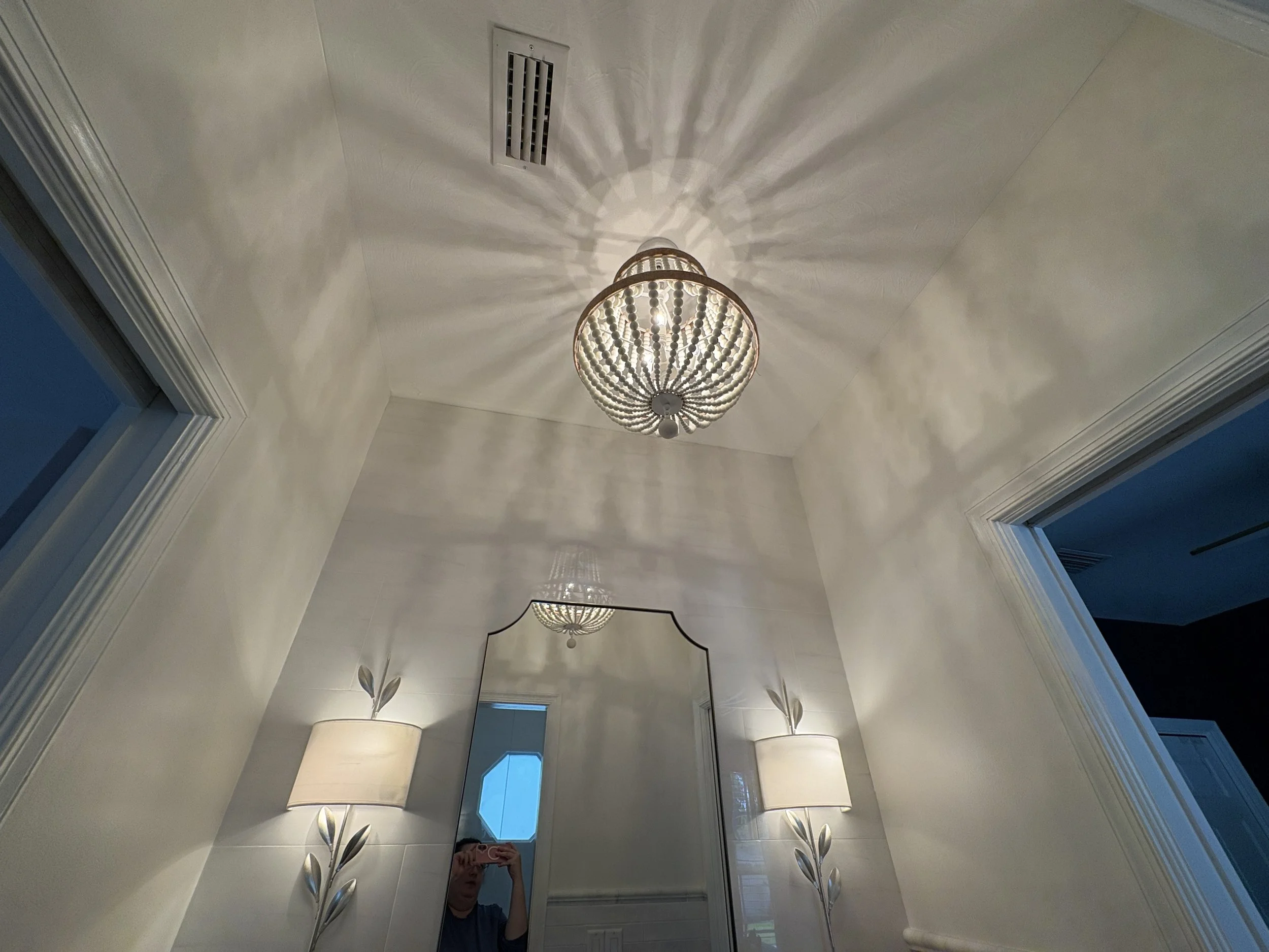 Finished bathroom featuring a decorative pendant light that serves as a striking focal point, casting elegant patterns across the vaulted ceiling and enhancing the room’s warm, inviting ambiance. Paired with custom wall sconces, refined trim details,