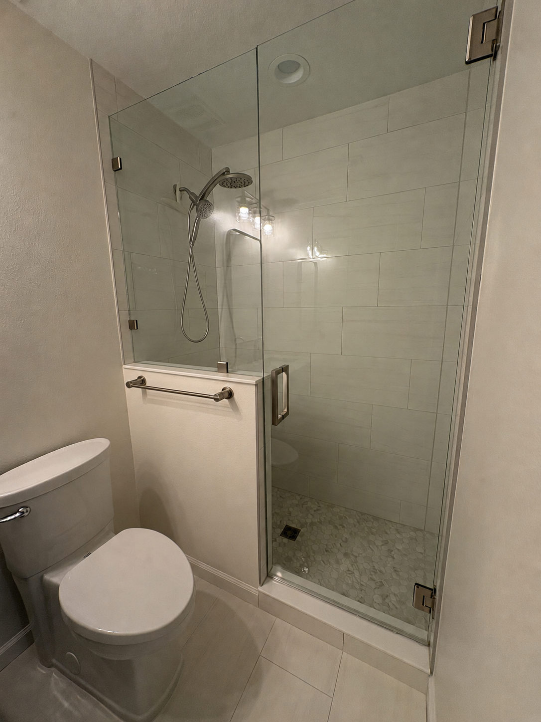 This luxury bathroom remodel features a frameless glass shower enclosure, large-format tile, and sleek modern fixtures as part of a high-end Jacksonville condo renovation by Elite Construction of JAX.