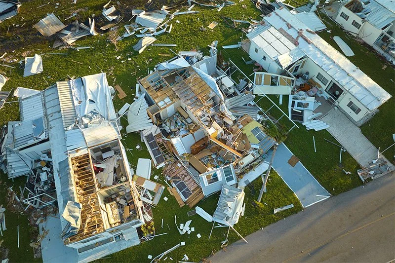 Aerial view of hurricane-damaged homes with debris scattered.
