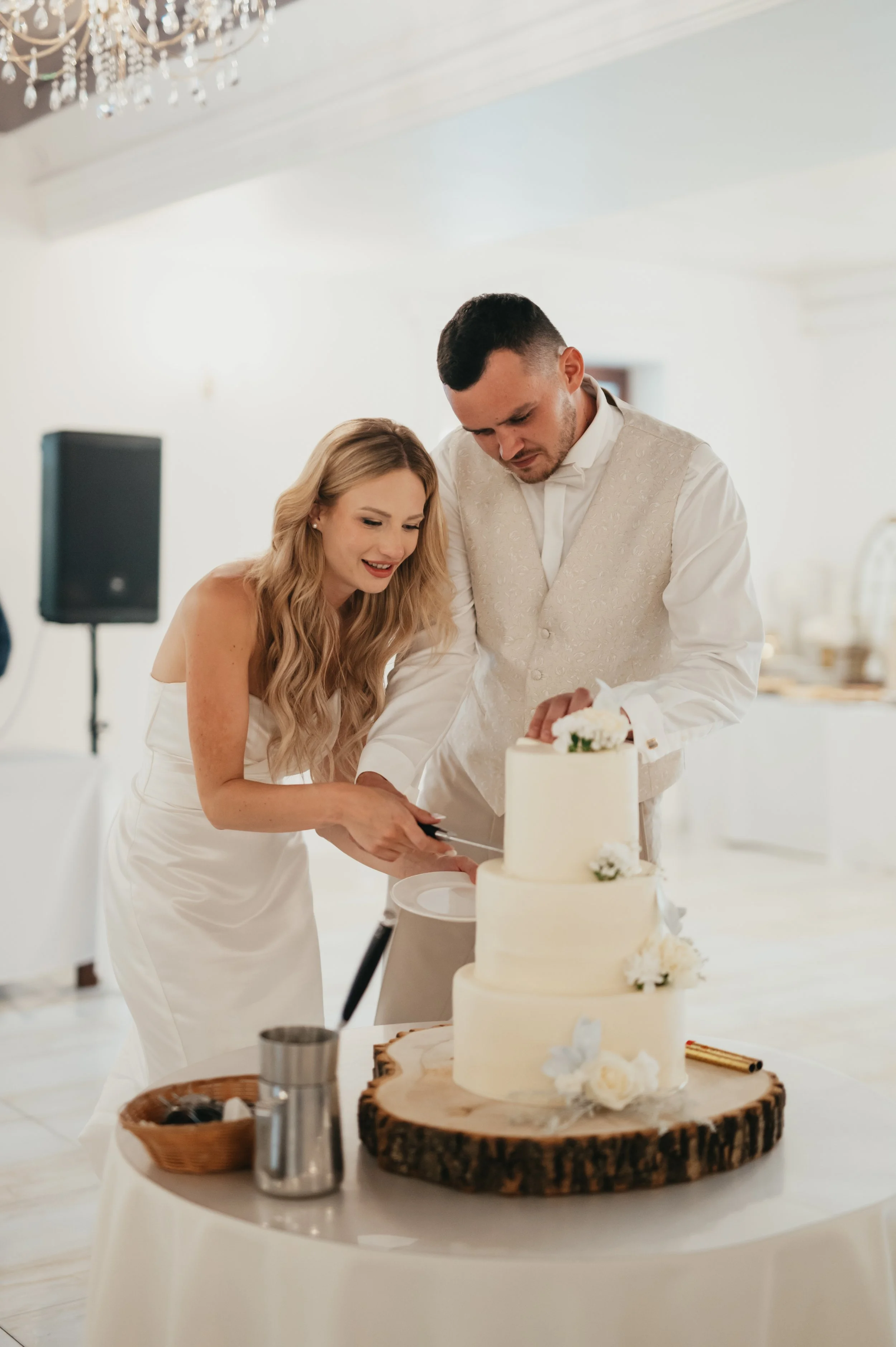 Bride and groom cutting a wedding cake together at a reception.