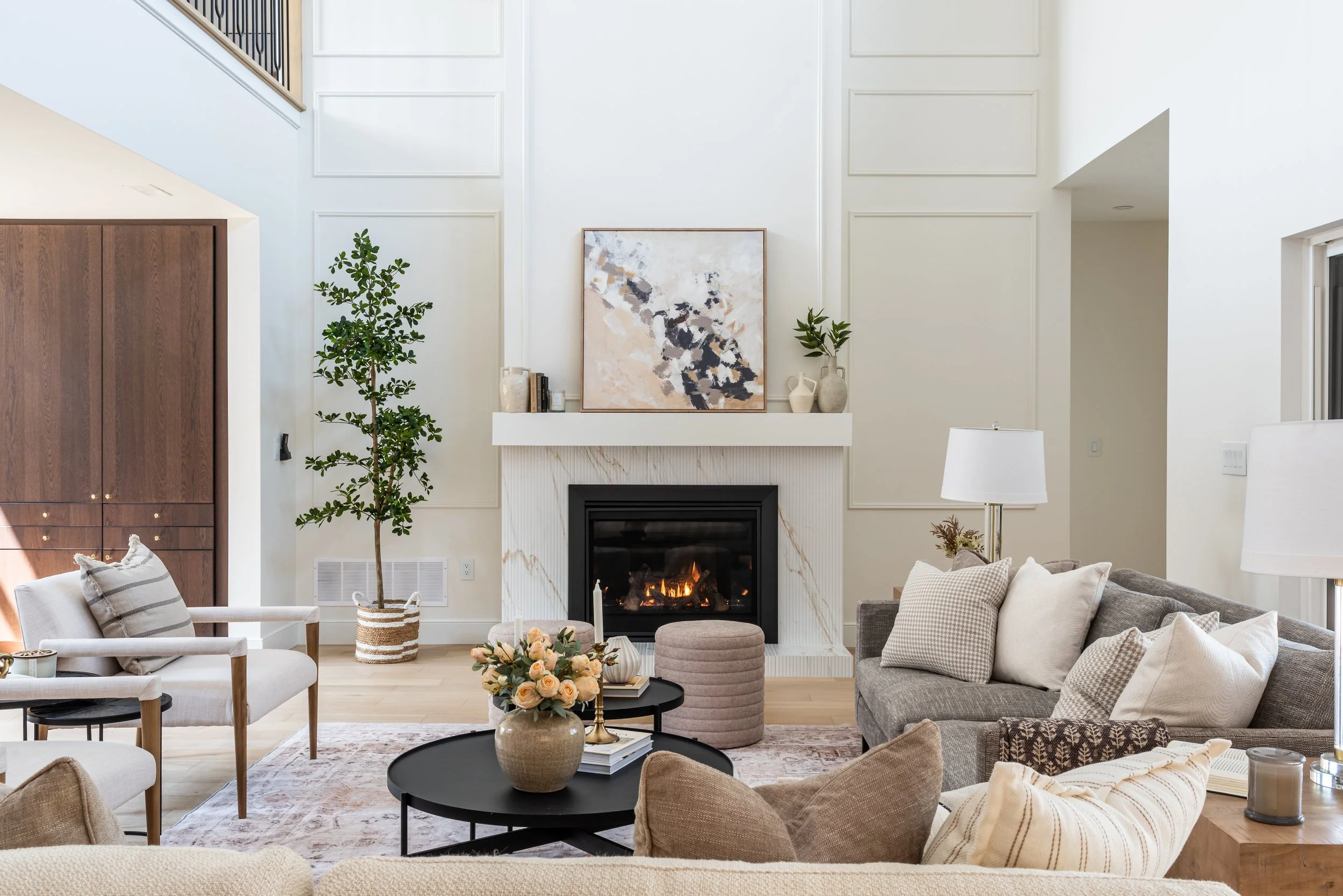 Elegant staged living room with fireplace, layered neutral textures, and natural light — showcasing how professional staging enhances home value.