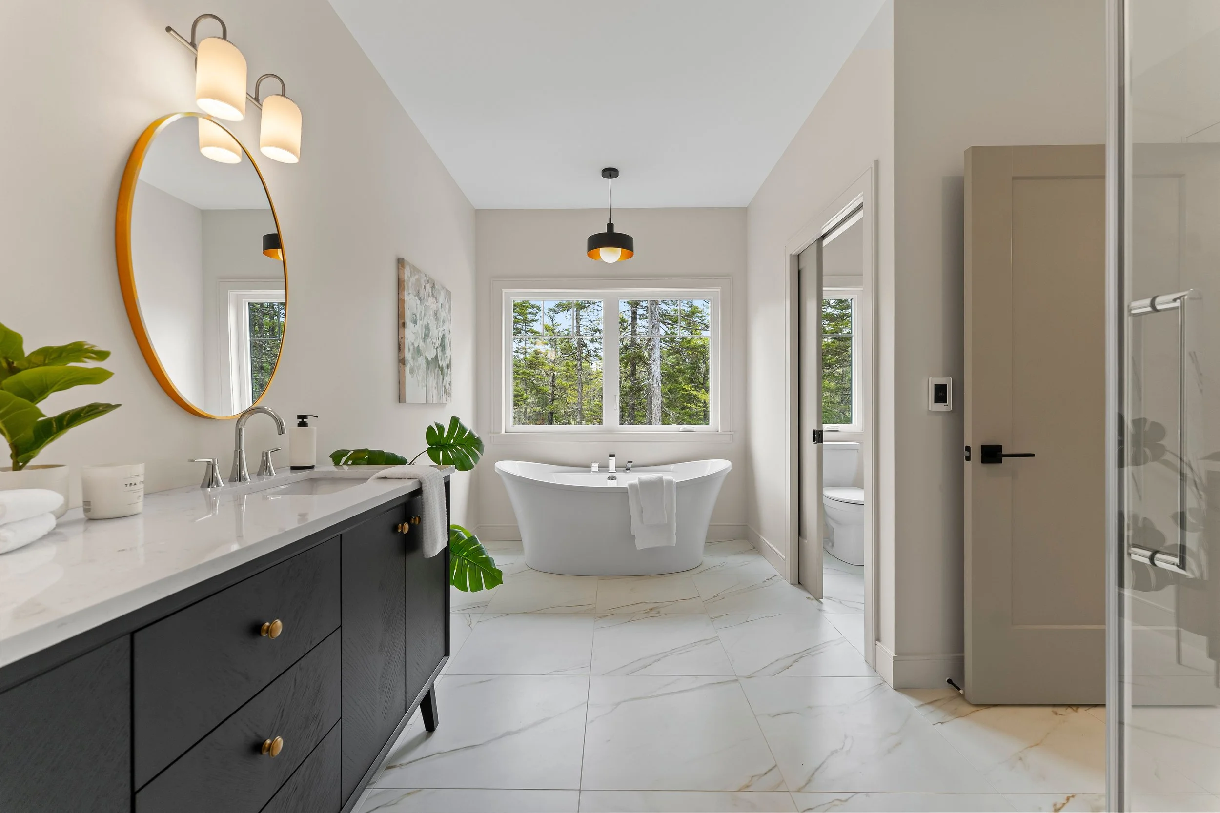 Professionally staged Halifax bathroom with warm vanity lighting, freestanding soaking tub, and large windows — Halifax real estate staging