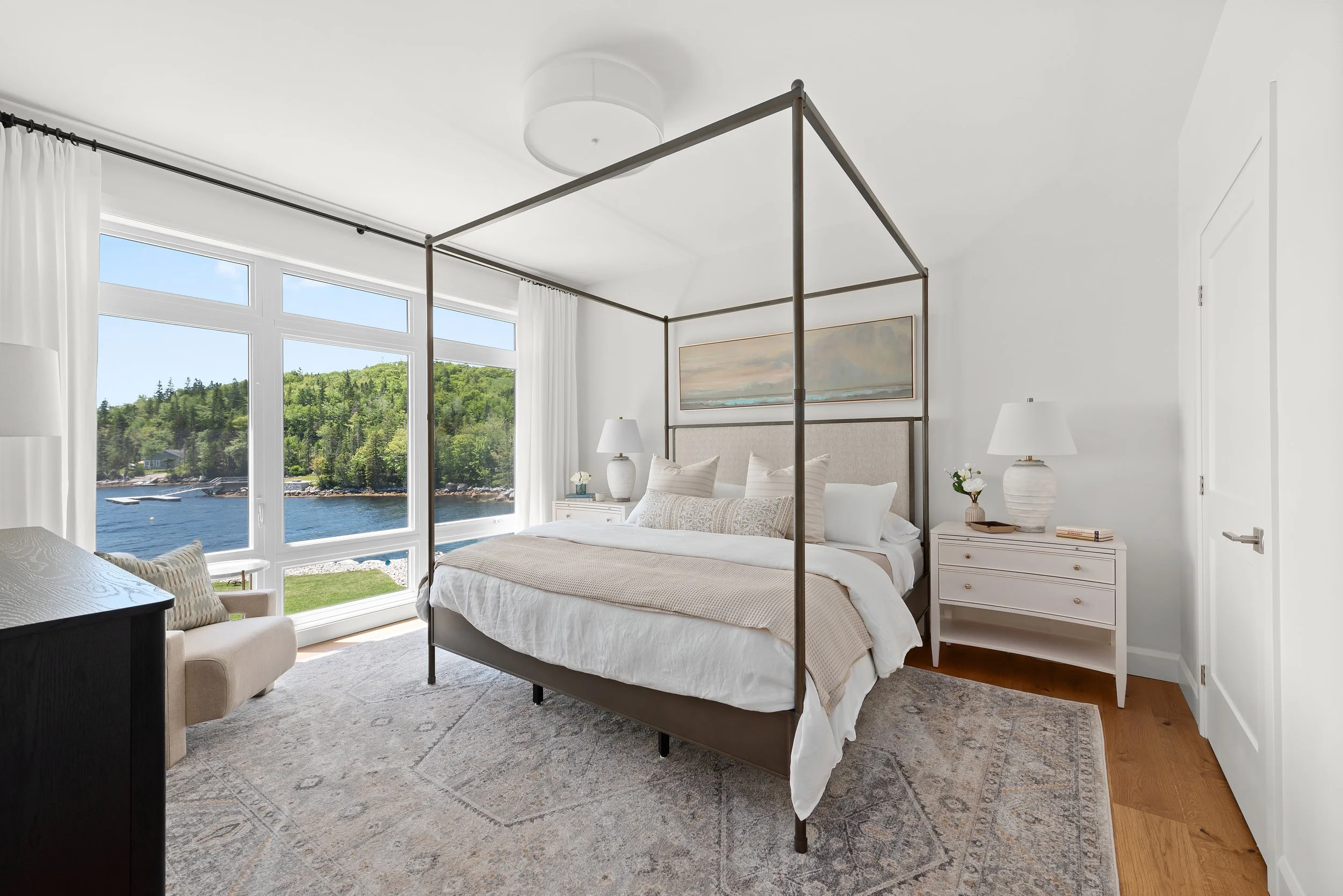 Bright primary bedroom with four-poster bed, sheer curtains, waterfront view, and soft natural light — professional bedroom staging Halifax NS