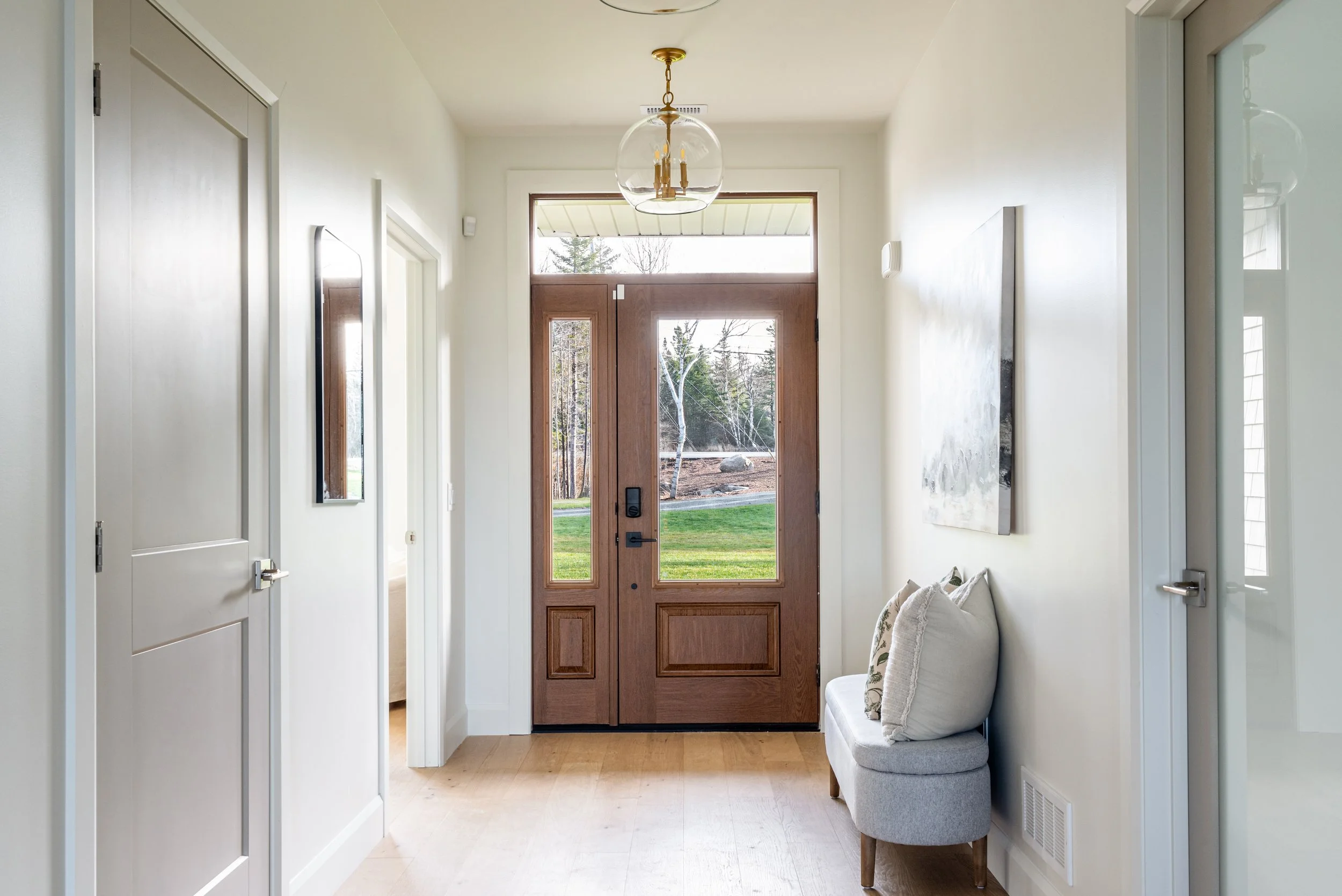 Bright, staged entryway in Halifax home with glass pendant light, wood front door, and natural light — home staging Halifax NS by Charlotte Interiors