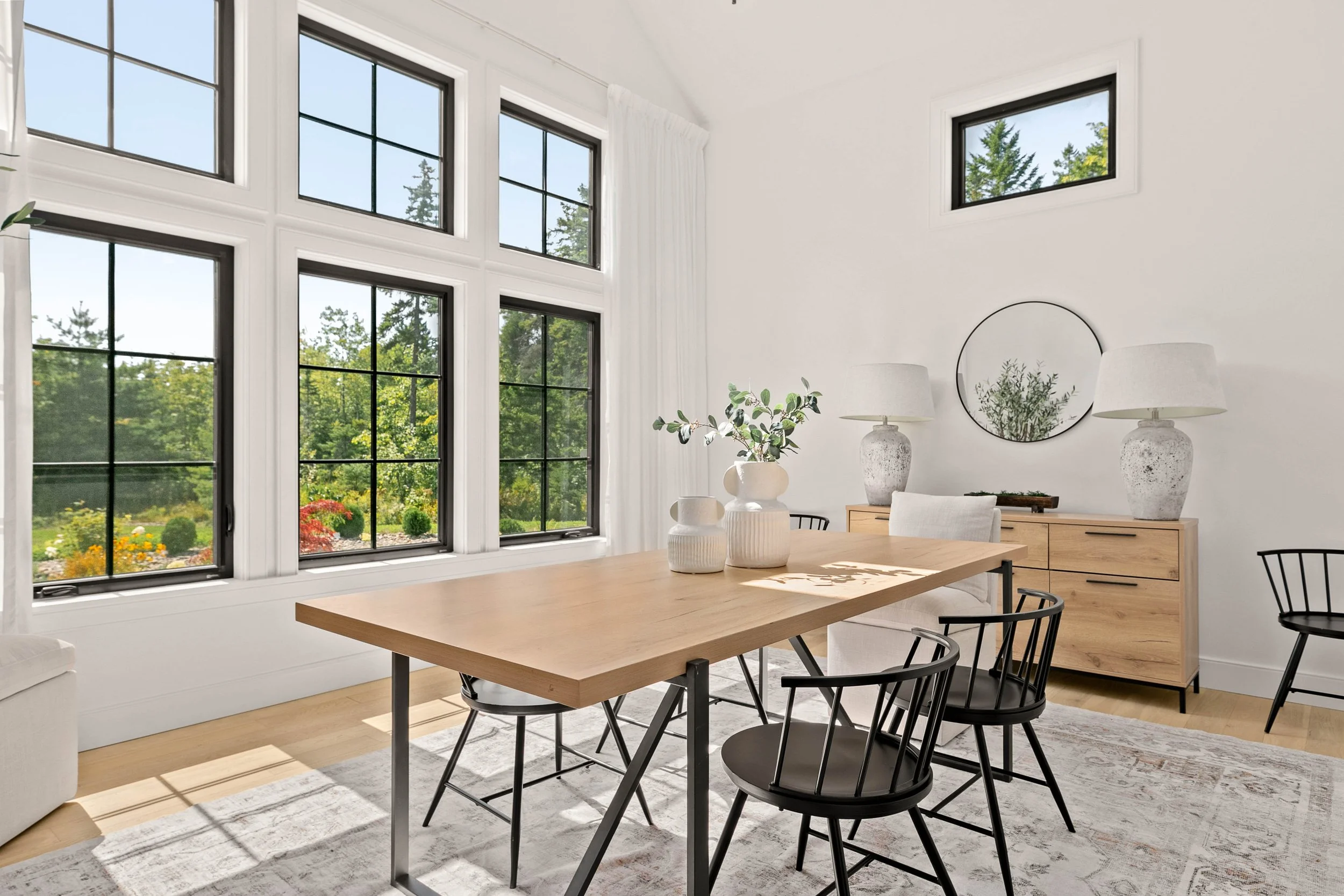 Sun-filled dining room with large black-framed windows, natural light, and minimalist staging — Halifax real estate staging by Charlotte Interiors