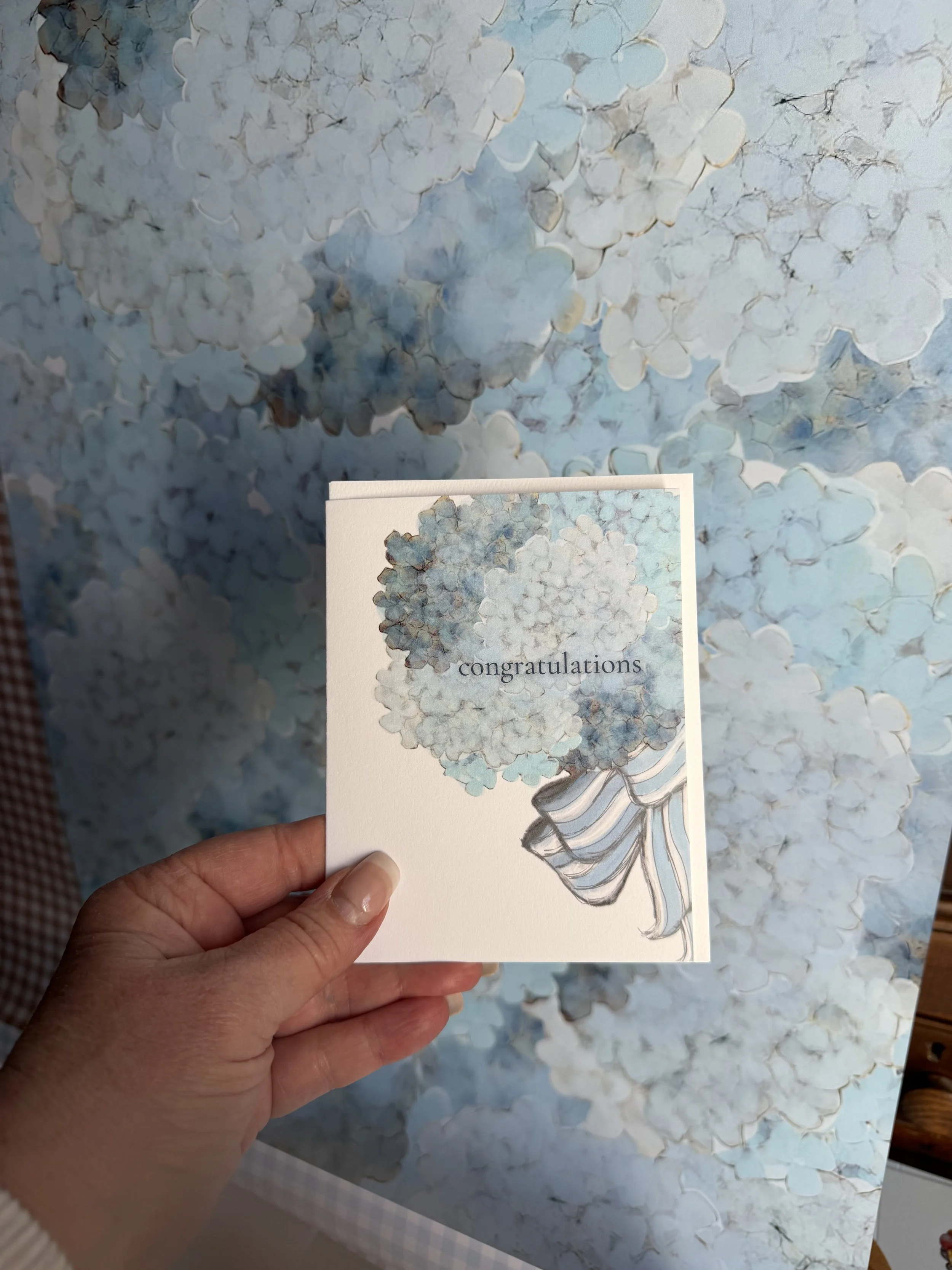 A notecard by Mary Draper Design with a hydrangea flower bouquet illustration with the word 'congratulations' on the front. Coordinating gift wrap is available also at https://www.marydraperdesign.net