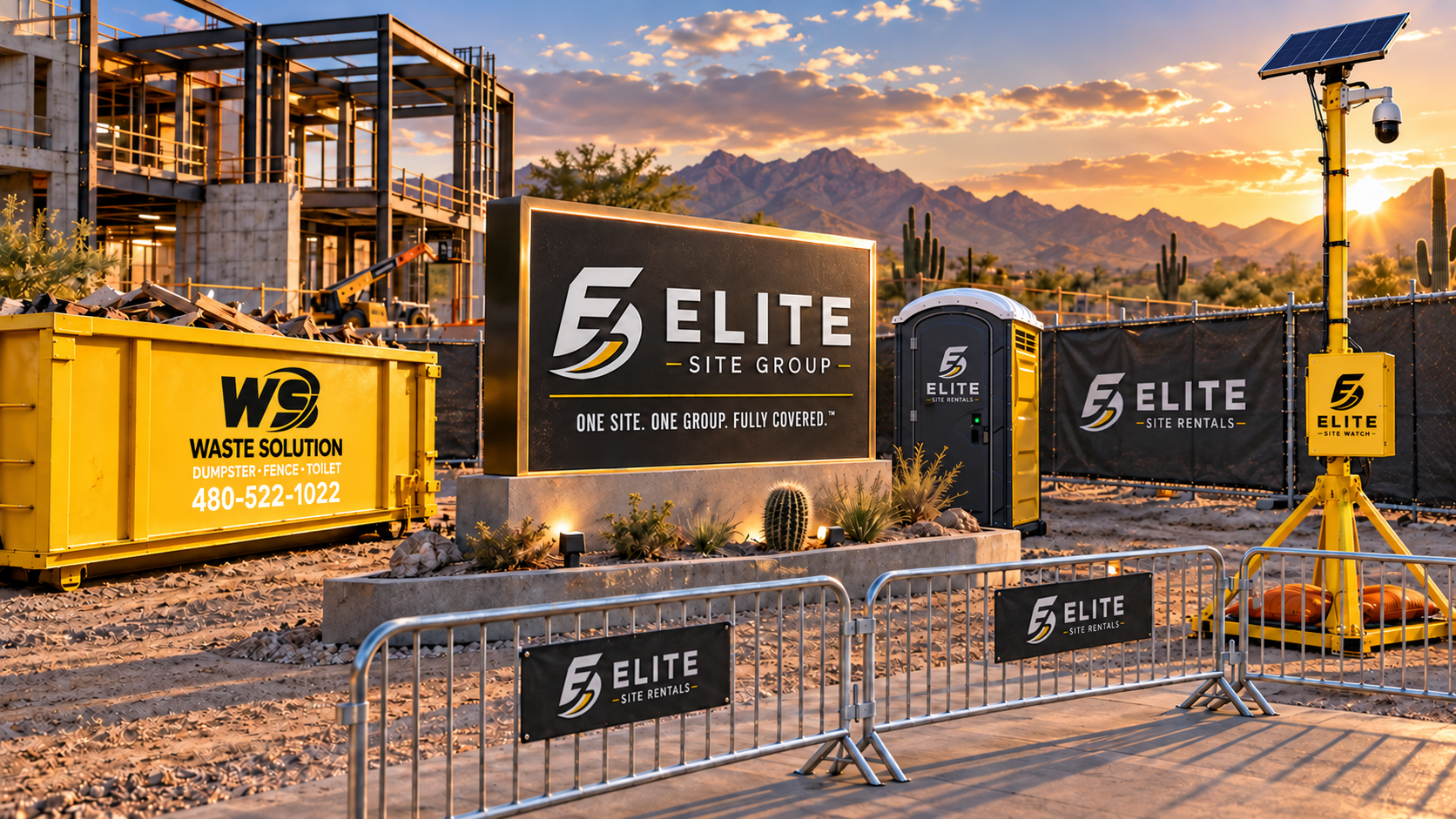 Construction site with a large illuminated sign for Elite Site Group, a portable toilet, a waste disposal container, construction fencing, solar-powered security cameras, and a desert landscape with cacti and mountains during sunset.