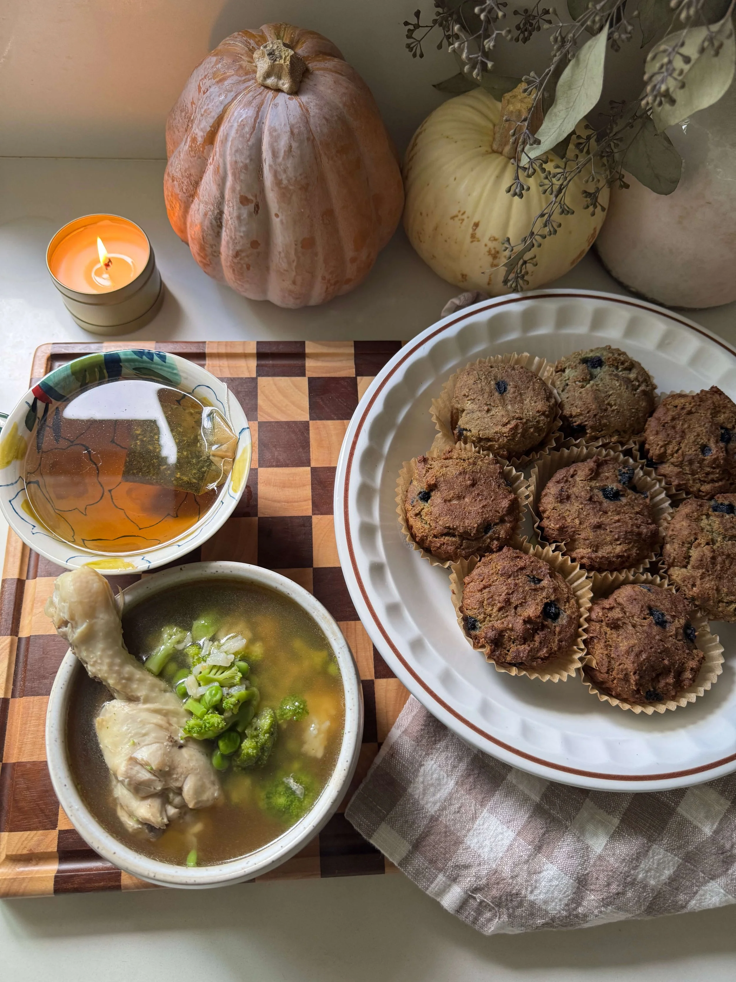 meal in plates and bowls on counter with candle soup muffins tea pumpkin