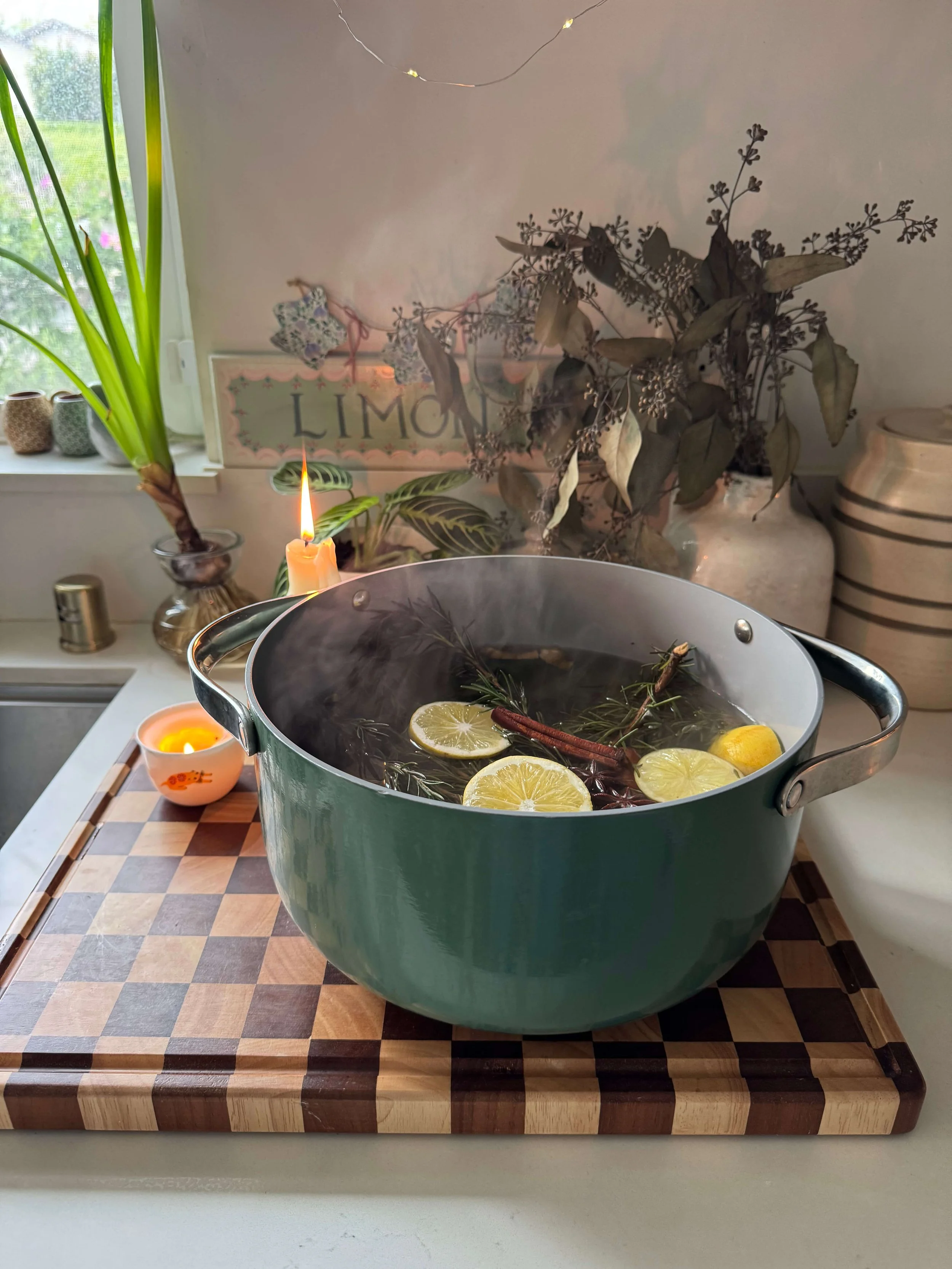 simmer pot on the counter in kitchen with steam lemon slices rosemary sprigs candles