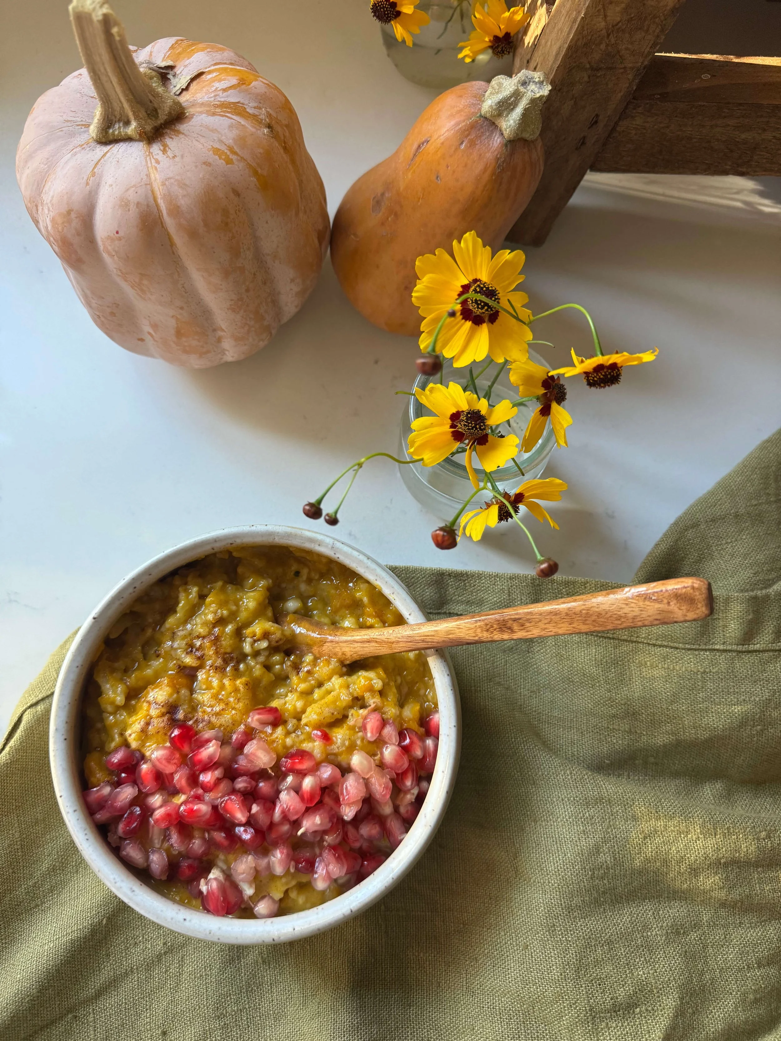congee in bowl in kitchen with pomegranate seeds pumpkin flowers autumn kitchen counter