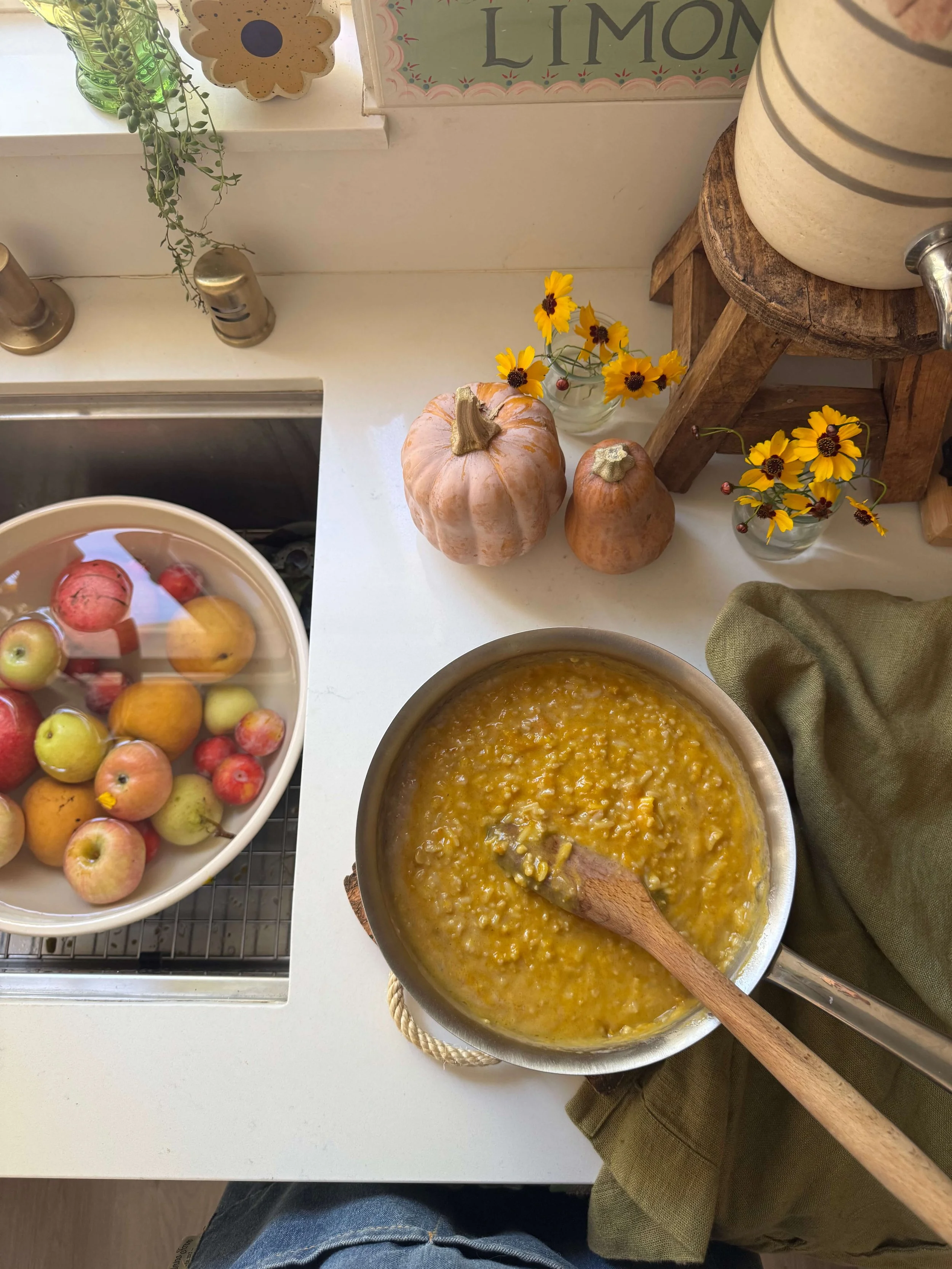 congee in bowl in kitchen with pomegranate seeds pumpkin flowers autumn kitchen counter